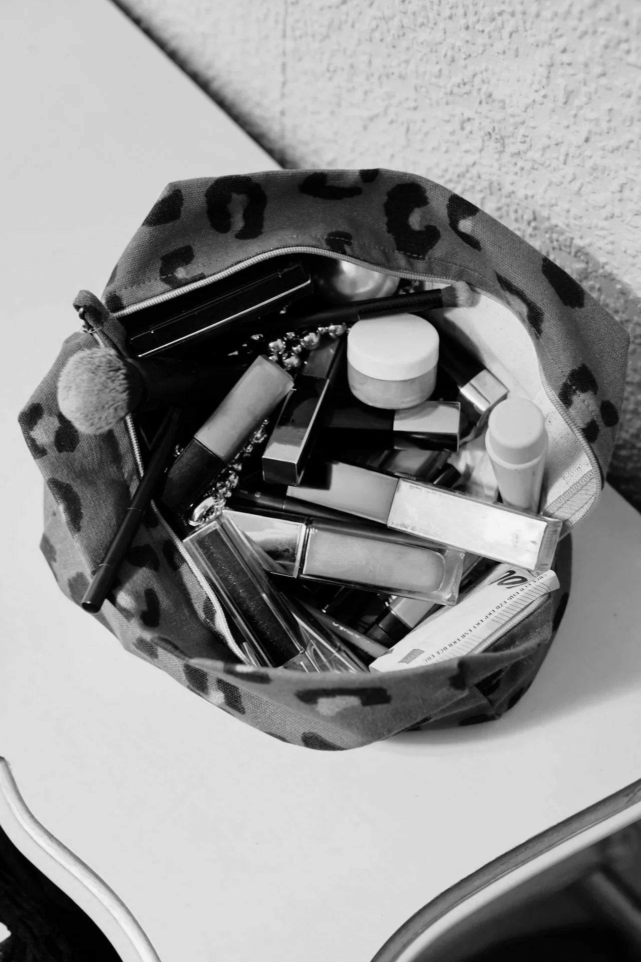 Woman in a robe getting makeup applied, smiling with closed eyes.