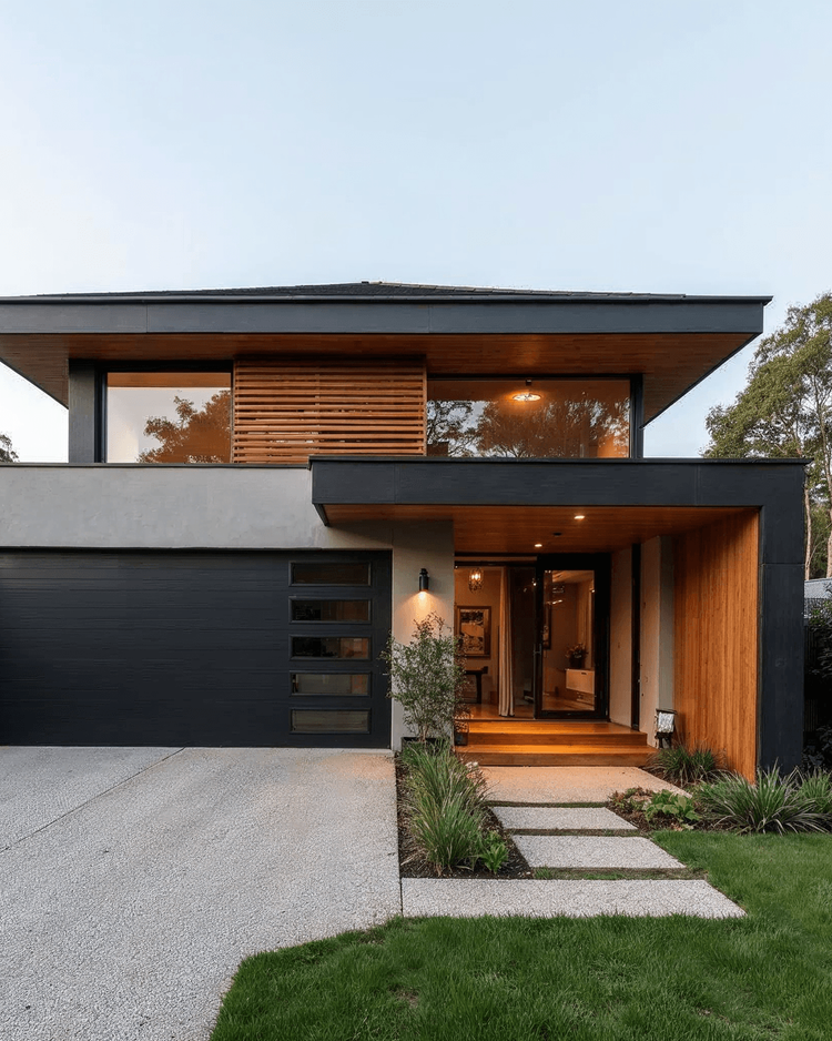 Contemporary two-story home facade with dark cladding, warm timber soffits, and a double garage
