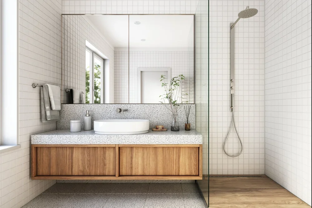 Minimalist bathroom setup with a floating terrazzo vanity countertop, light timber drawers, and a walk-in shower with grid wall tiles