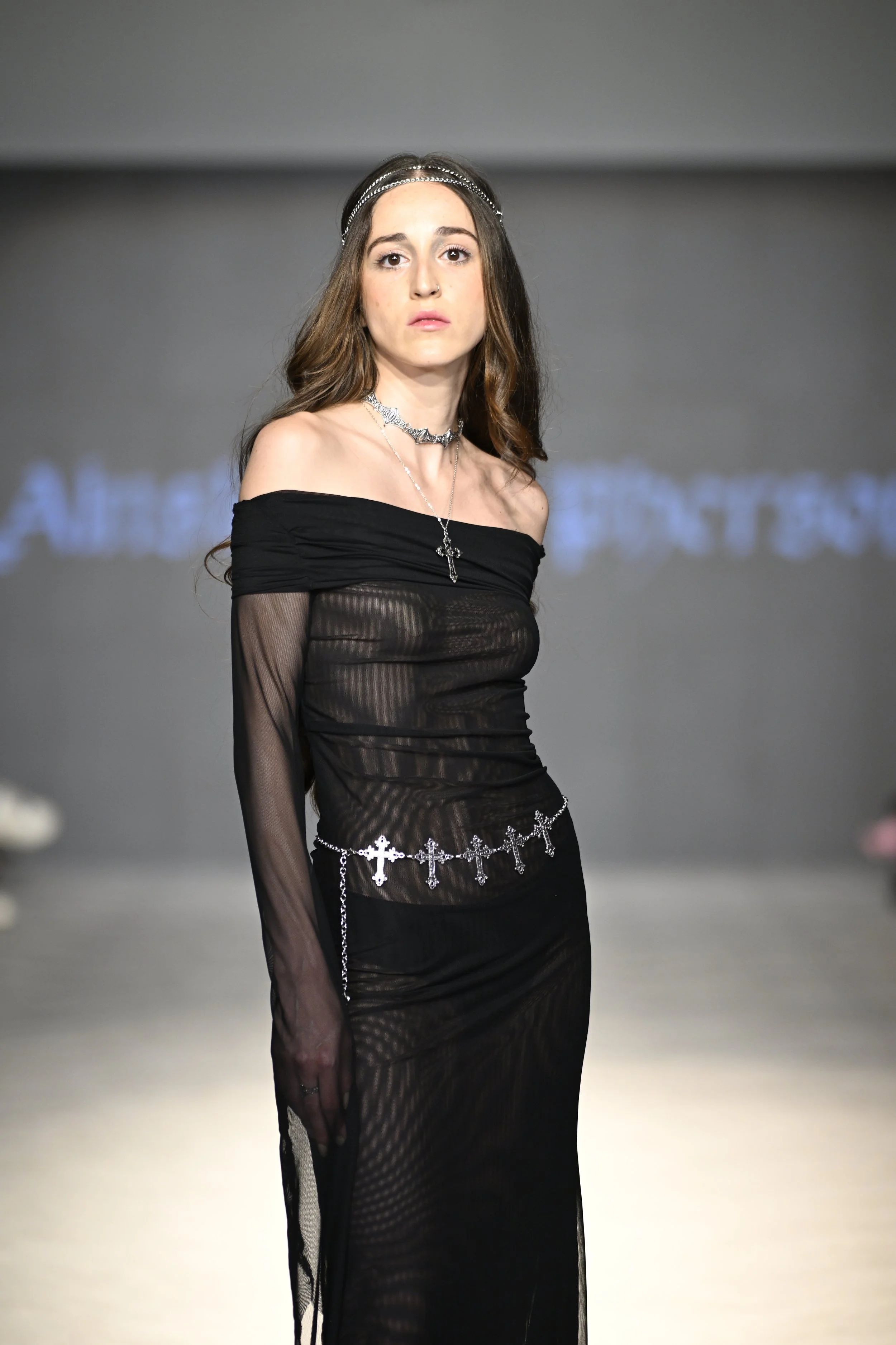 Krysta wears a black mesh medieval-inspired off-shoulder dress with extended sleeves, and a handmade chain headpiece.