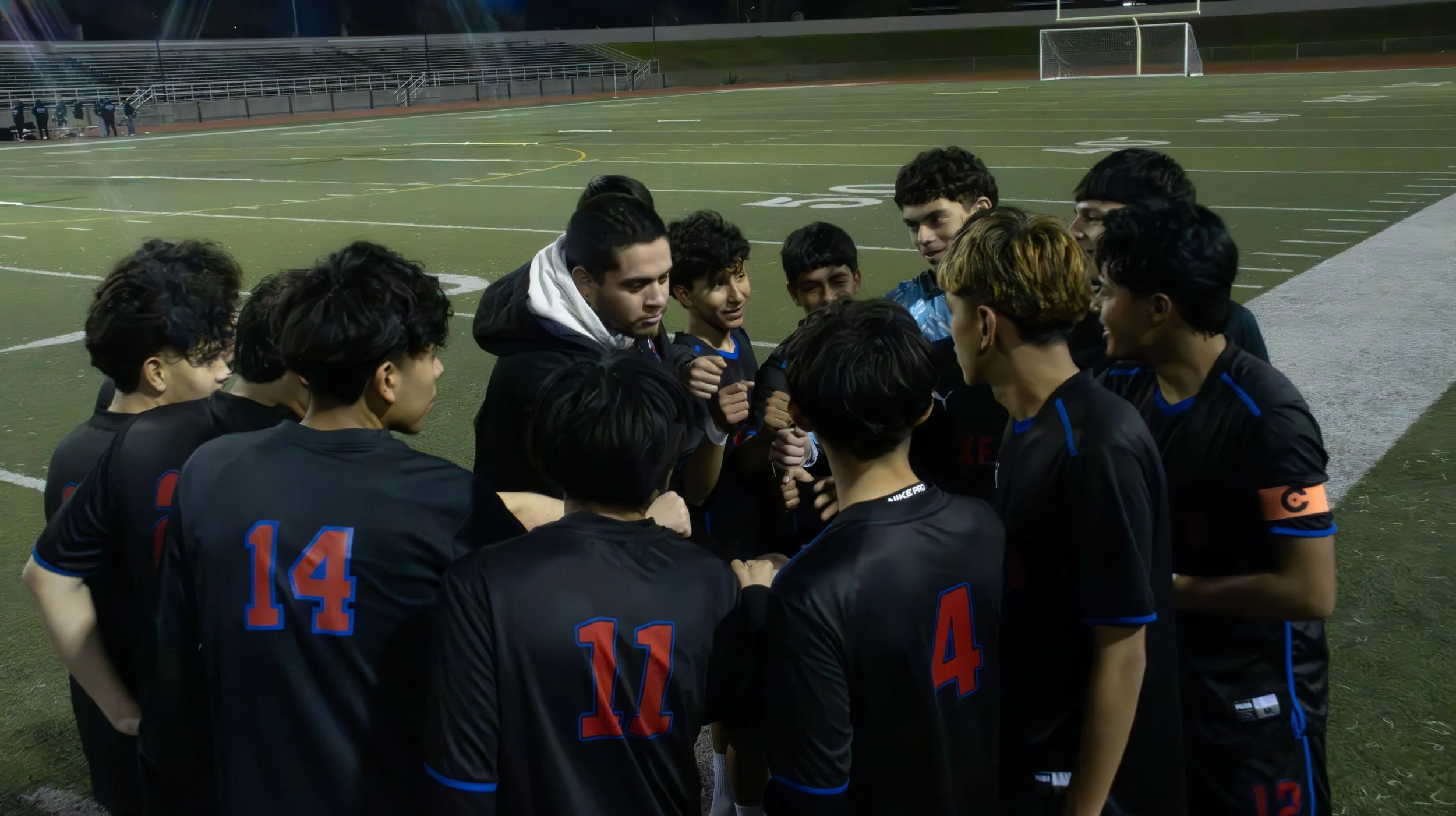 A soccer team huddled on a field