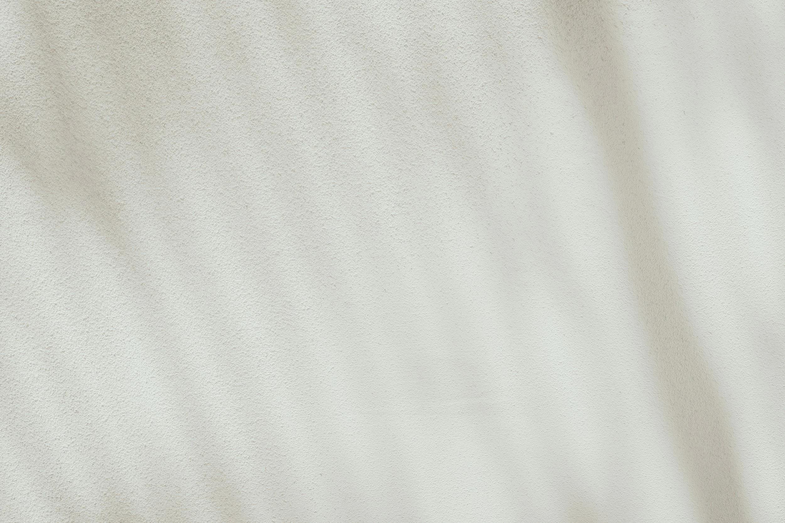 Close-up of a textured off-white wall with a shadow on the right side.