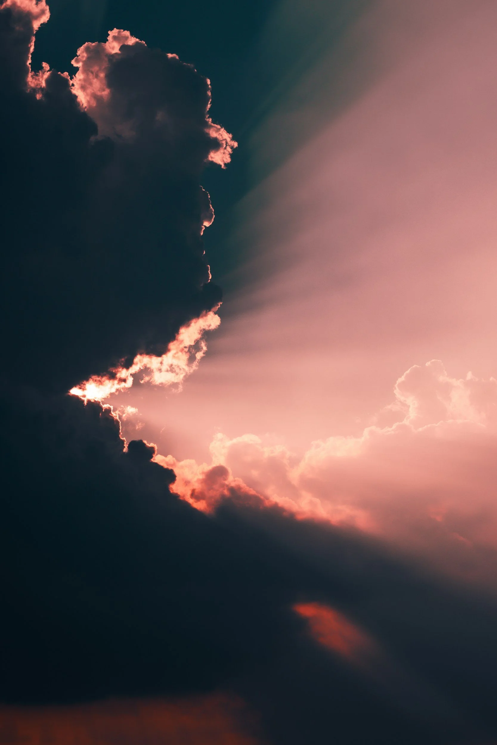 Sky with dark clouds and sun rays shining through, creating a dramatic lighting effect.