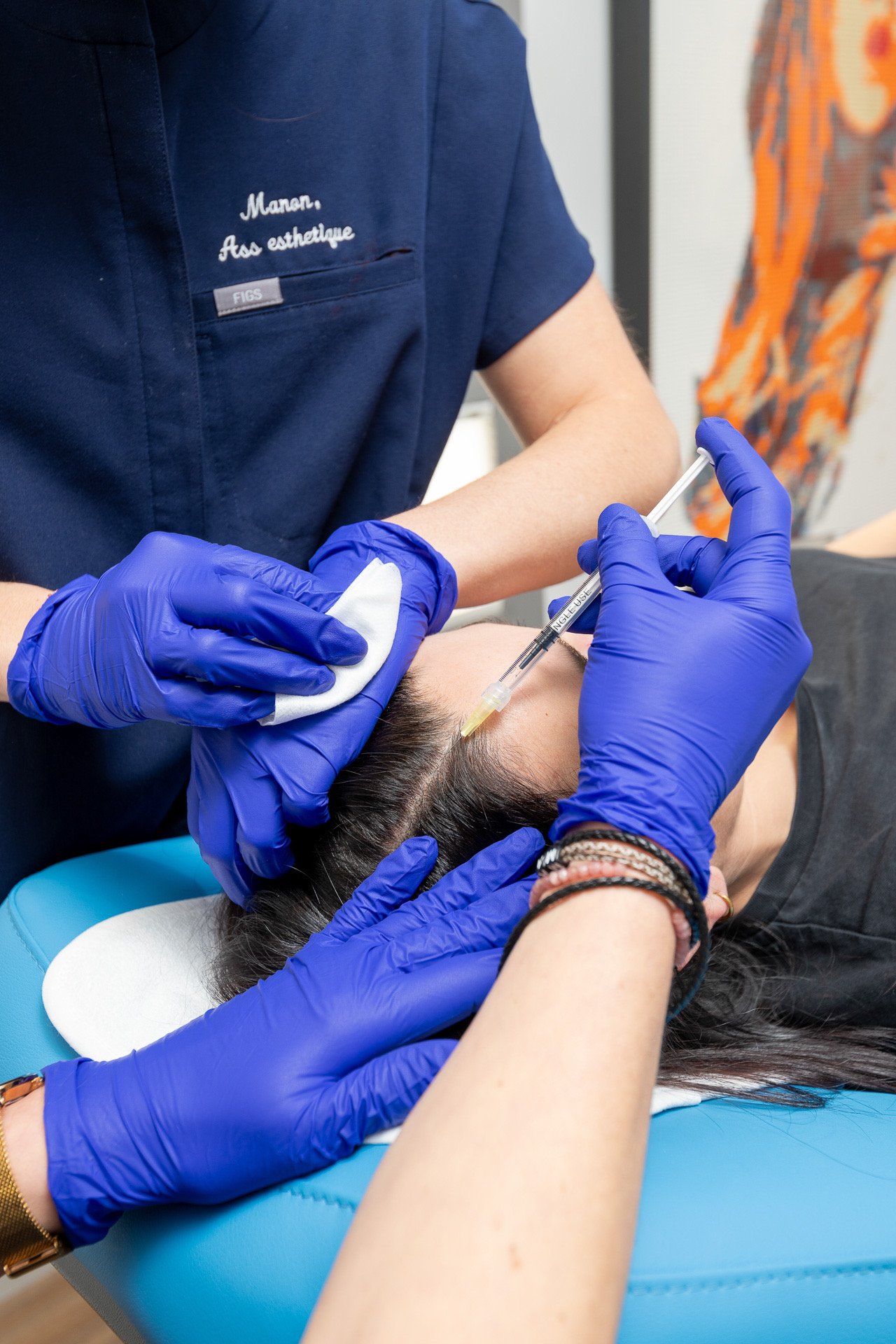 Une personne reçoit une injection dans le bras, administrée par un professionnel avec des gants en latex bleus.