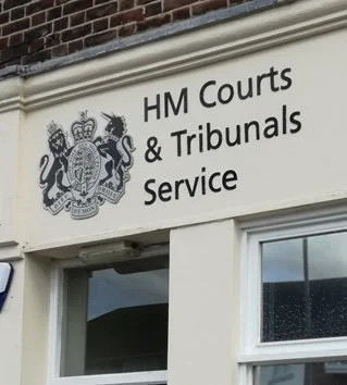 Sign for HM Courts & Tribunals Service on a building with a royal coat of arms emblem above it.