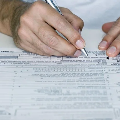 Person filling out a tax form with a pen