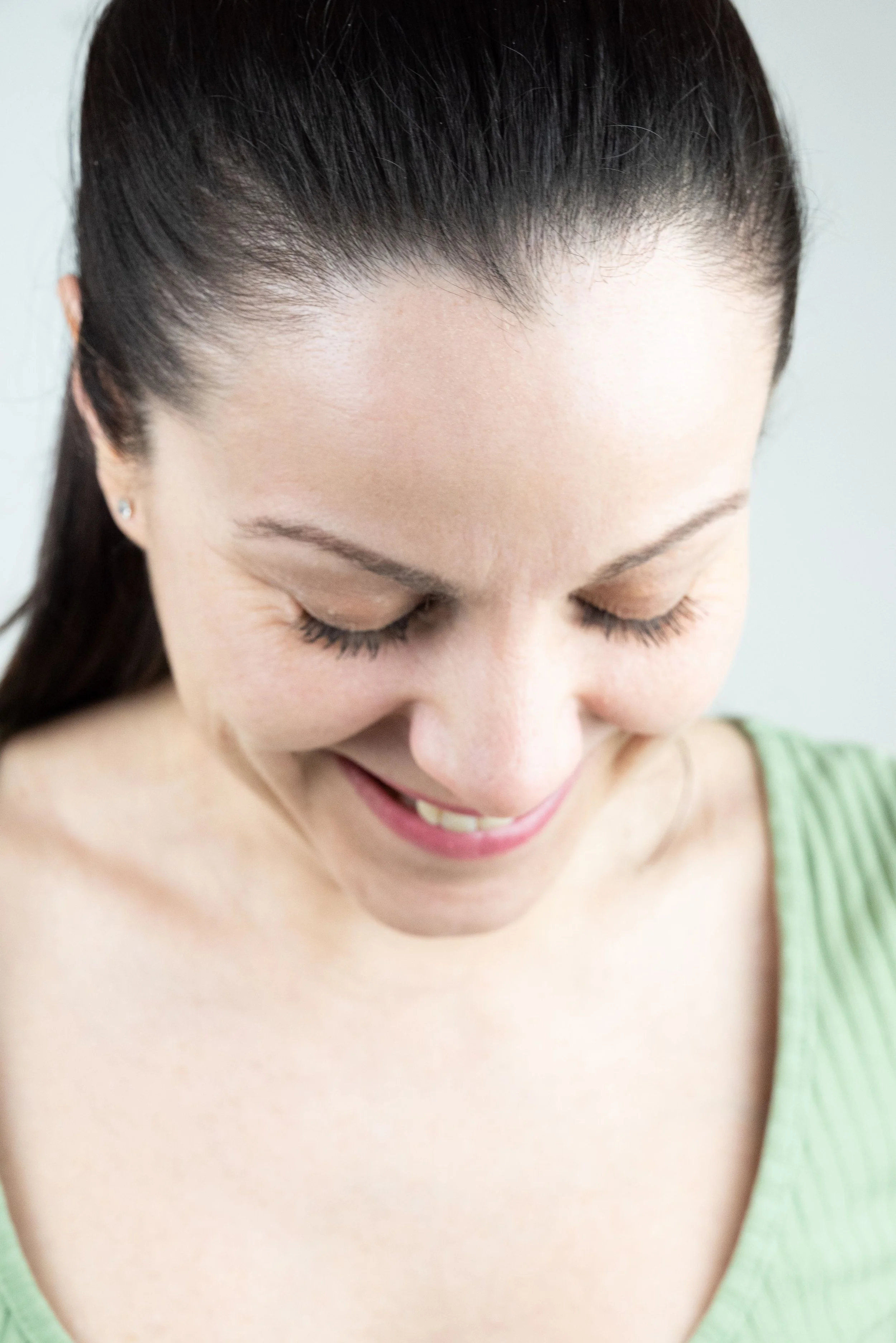 Portrait de l'actrice Sandrine Gauthier, souriante avec les yeux fermés, portant un haut vert, vue de face en gros plan.