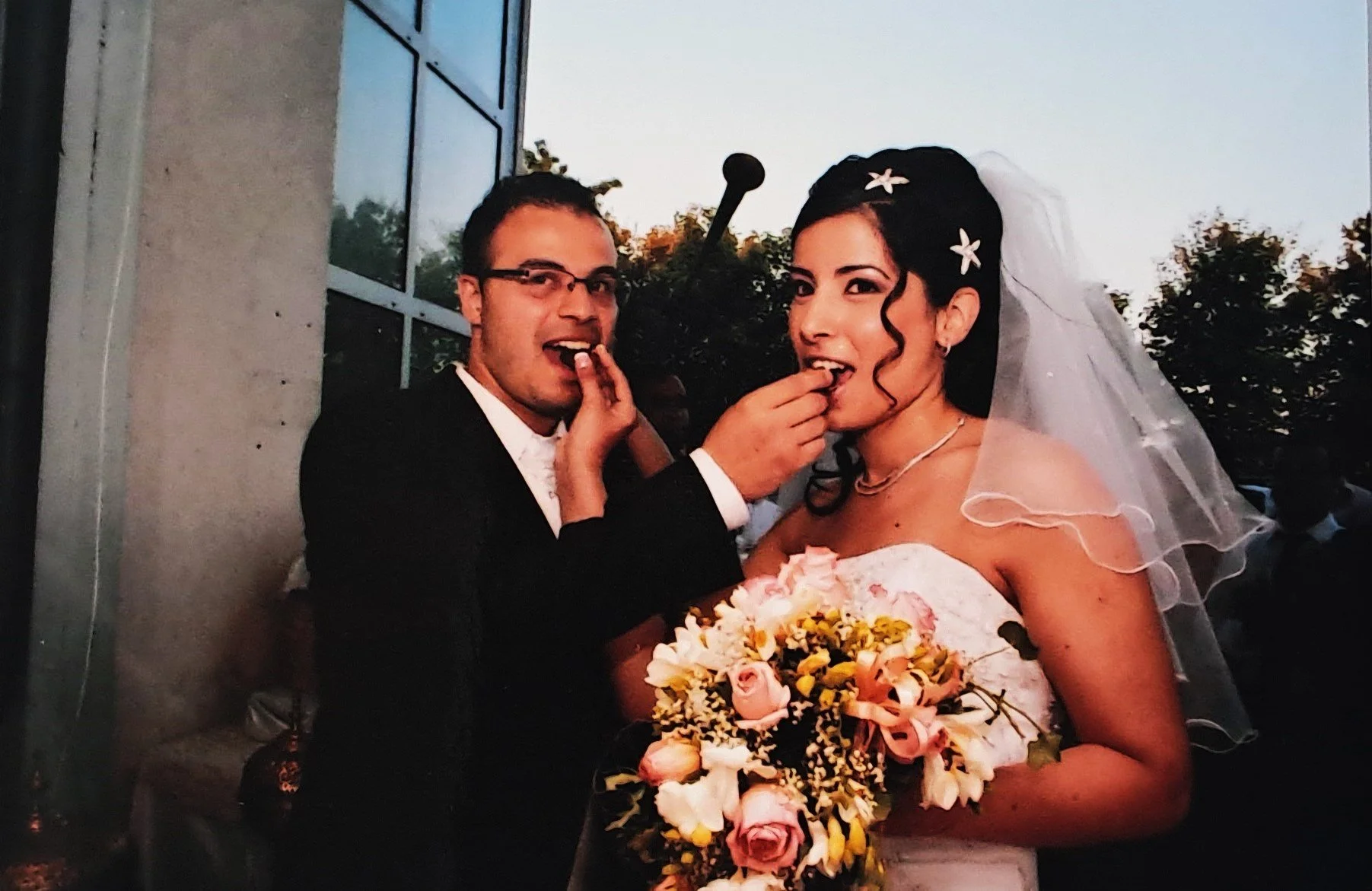 Un couple de mariés qui partage un moment ludique lors de leur mariage, en train de manger un gâteau.