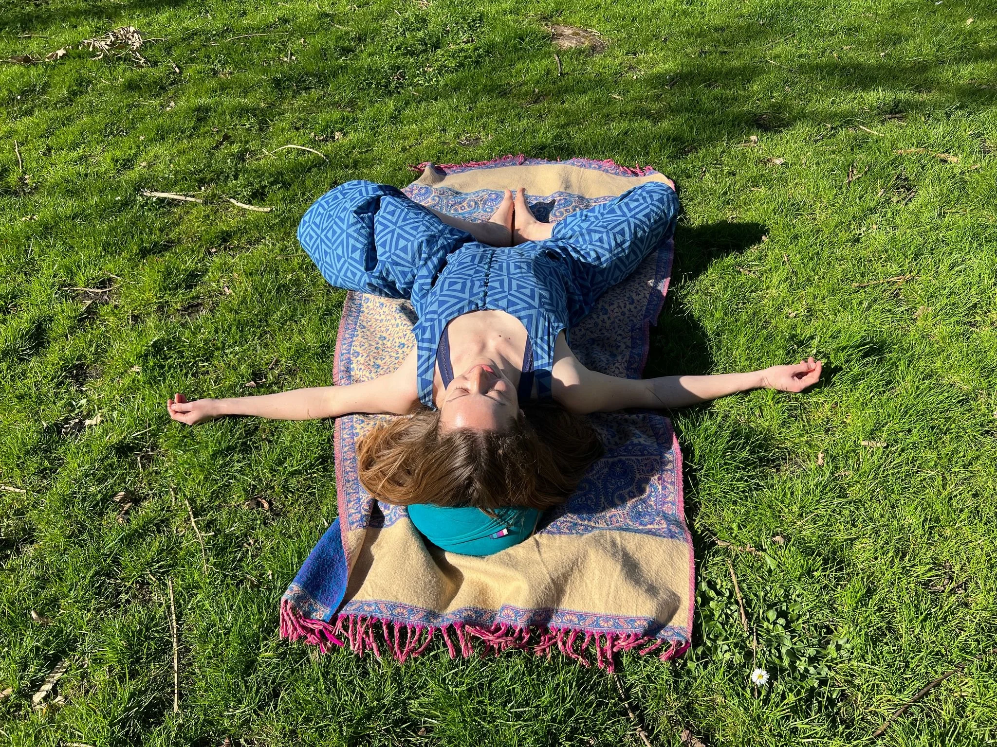 Woman lying on a bolster in the park in supta badha konasana or butterly pose