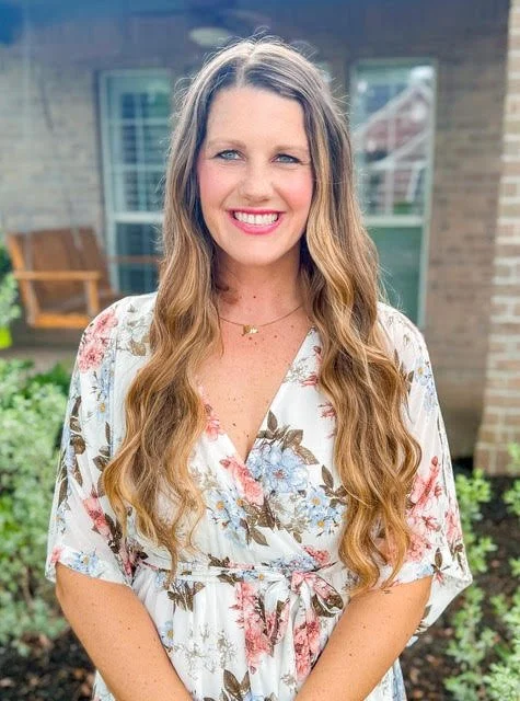 Stacey Robinson LPC-A headshot, Stacey stands smiling in front of a comfortable porch