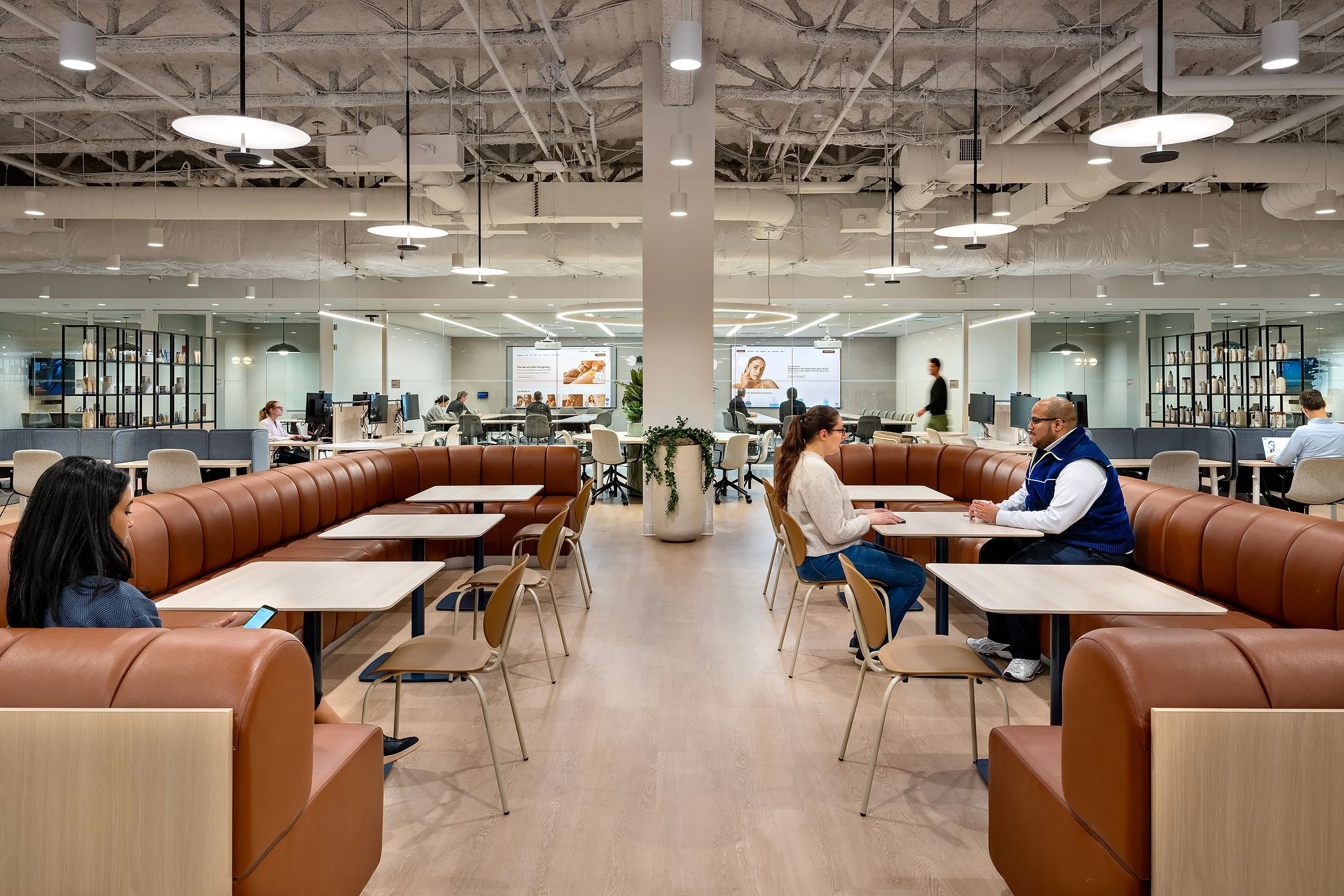 People sitting and talking in a modern kantoor with open layout, high ceilings, and bright lighting.