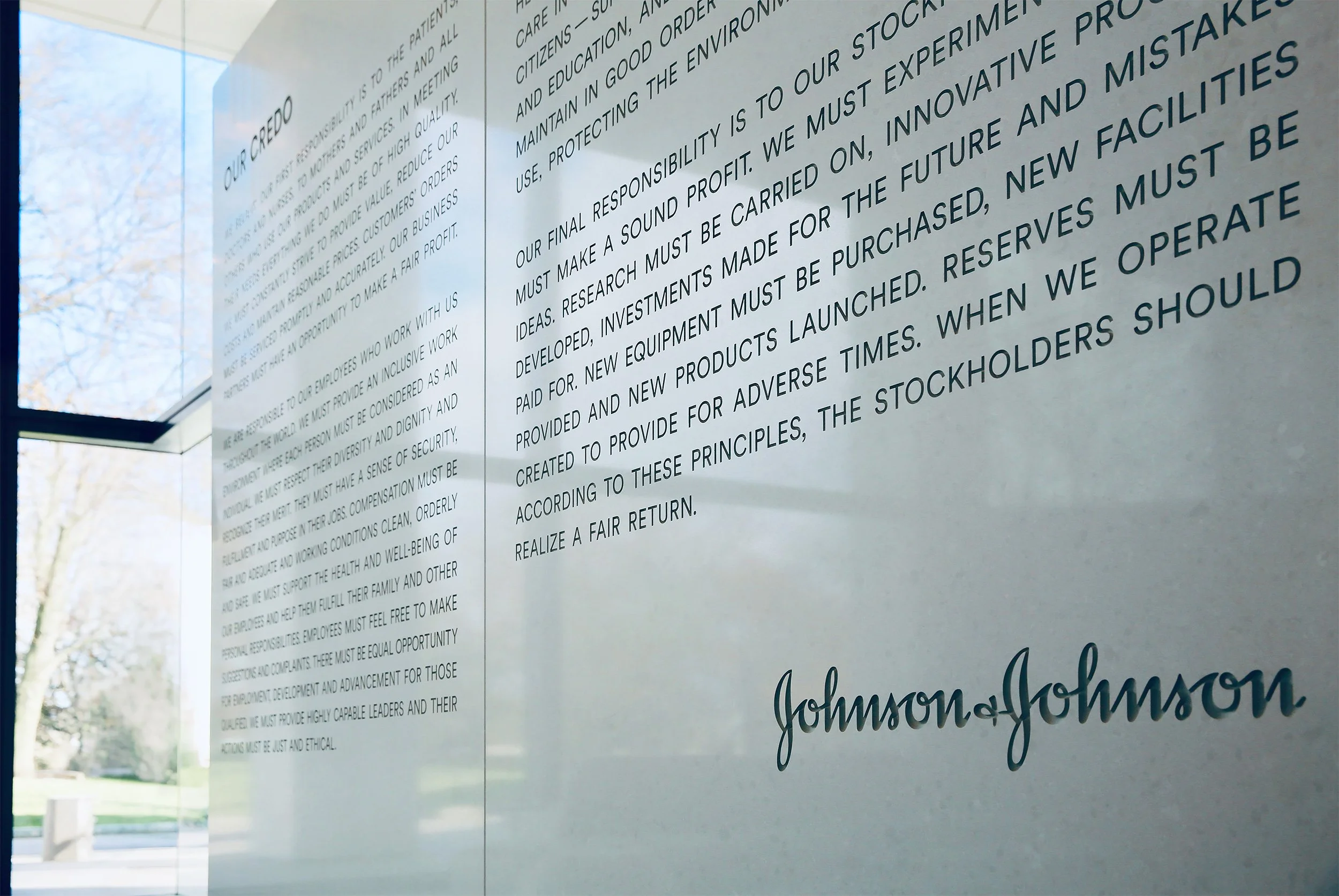 A framed mission statement or company credo with text detailing the company's values and responsibilities, including Johnson & Johnson logo at the bottom right.