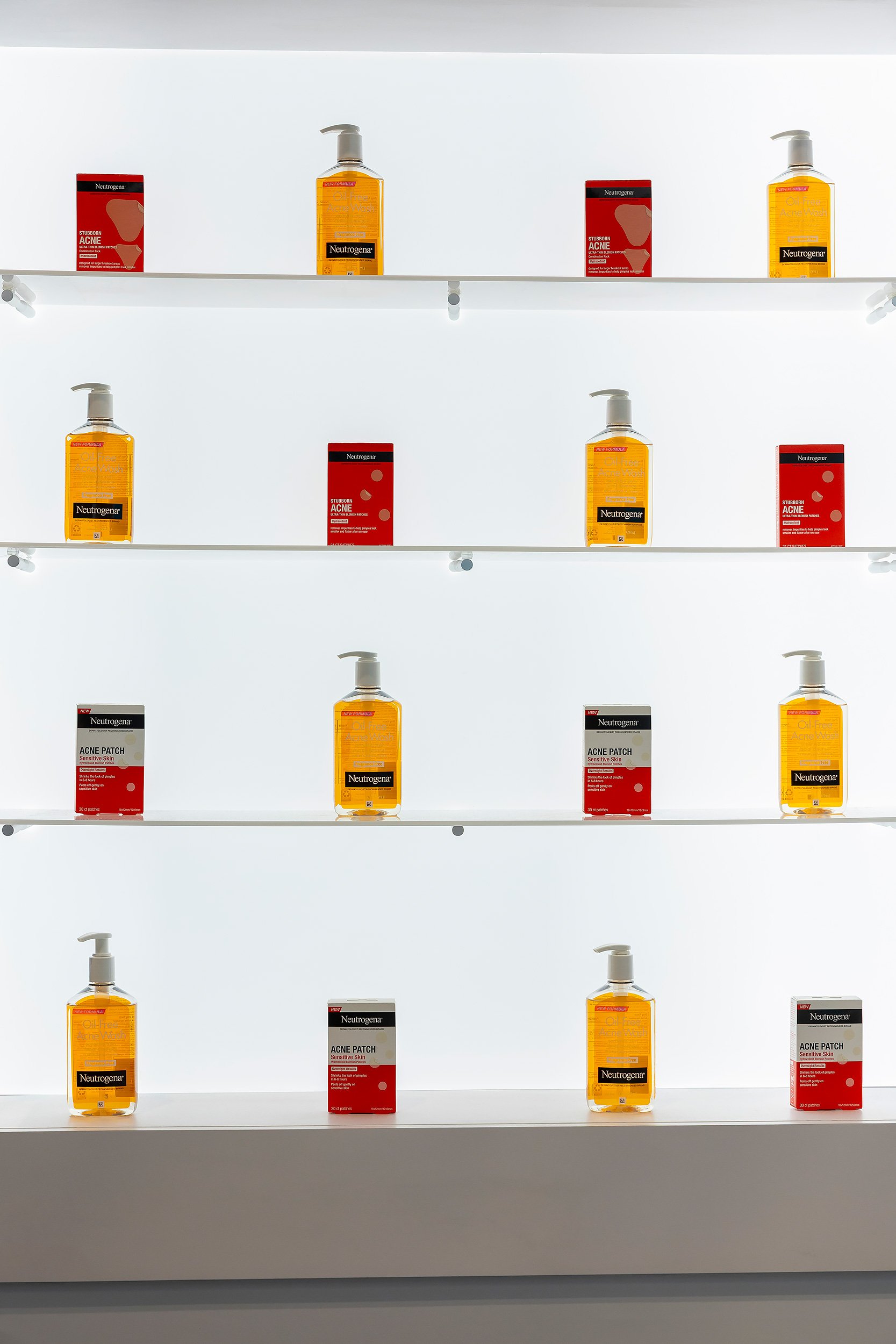 White shelves displaying bottles of Neutrogena acne wash and boxes of acne patch products, arranged in a neat pattern against a white background.