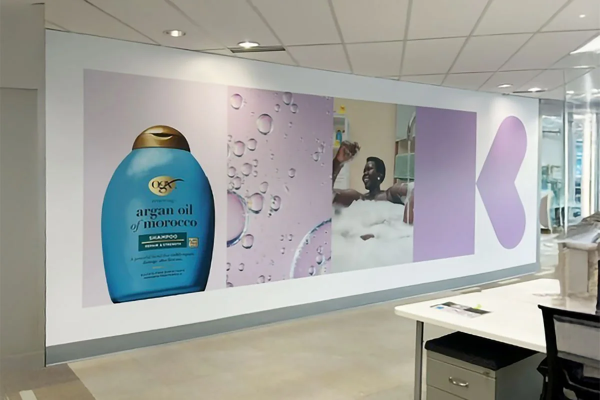 Advertising wall featuring a bottle of argan oil of Morocco shampoo, water bubbles, and two men enjoying a bath with foam.