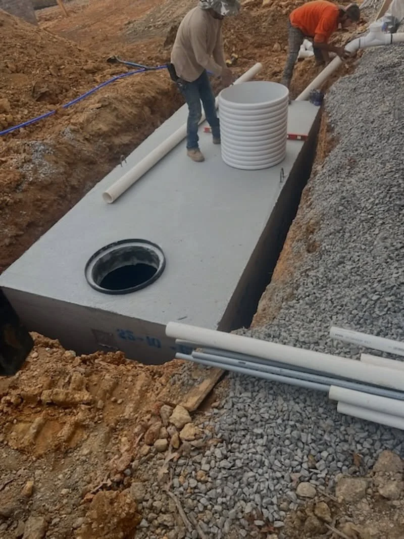 Septic Tank Installation in Progress

A concrete septic tank being set into place. The crew is positioning the tank in the excavation, installing the inlet/outlet piping, and preparing the riser for access once the system is covered. Proper leveling,