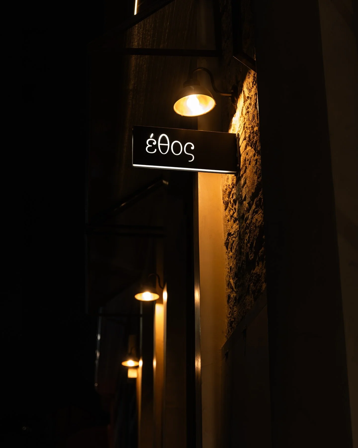 A dimly lit sign with the numbers 2023 upside down, illuminated by a warm light, mounted on a wall of stone and wood.