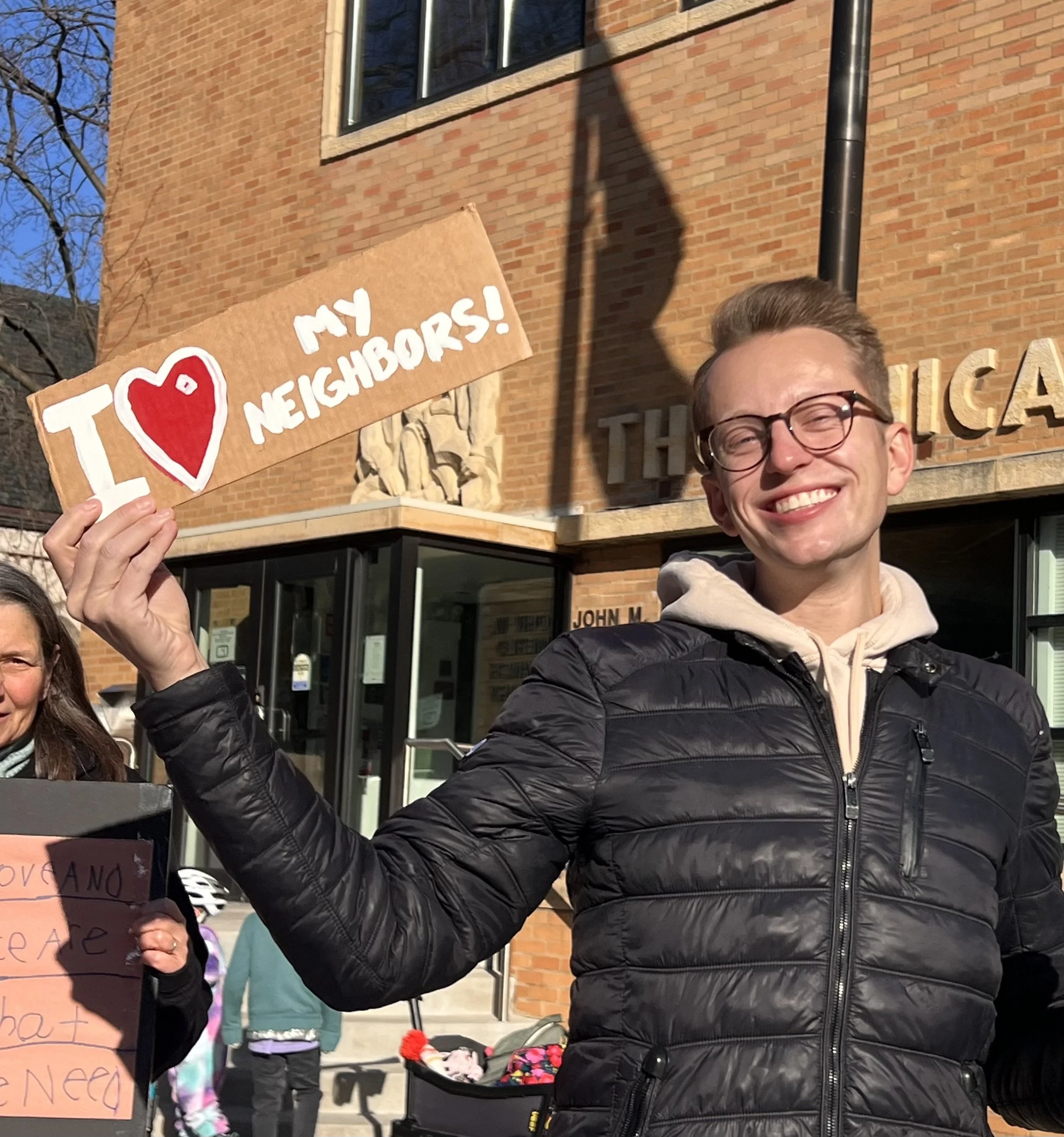 Smily Nick holds a sign that says "I love my neighbors!"