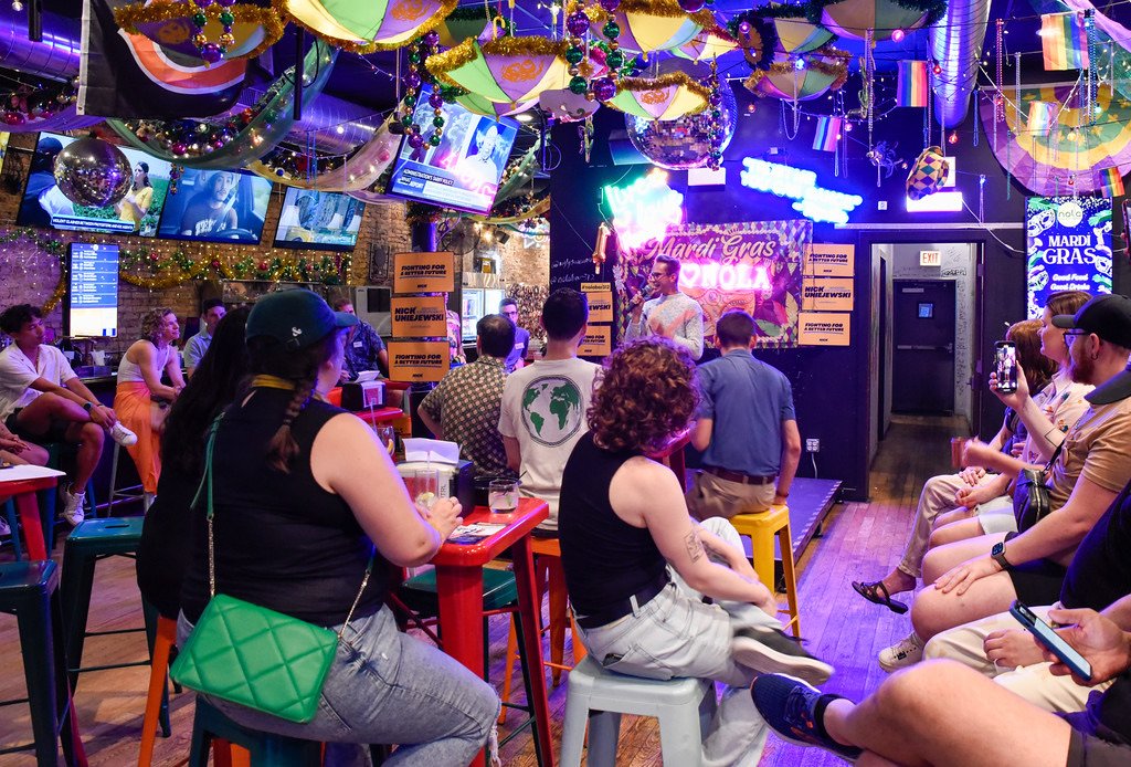 Nick speaking to a crowd at a bar decorated for Mardi Gras