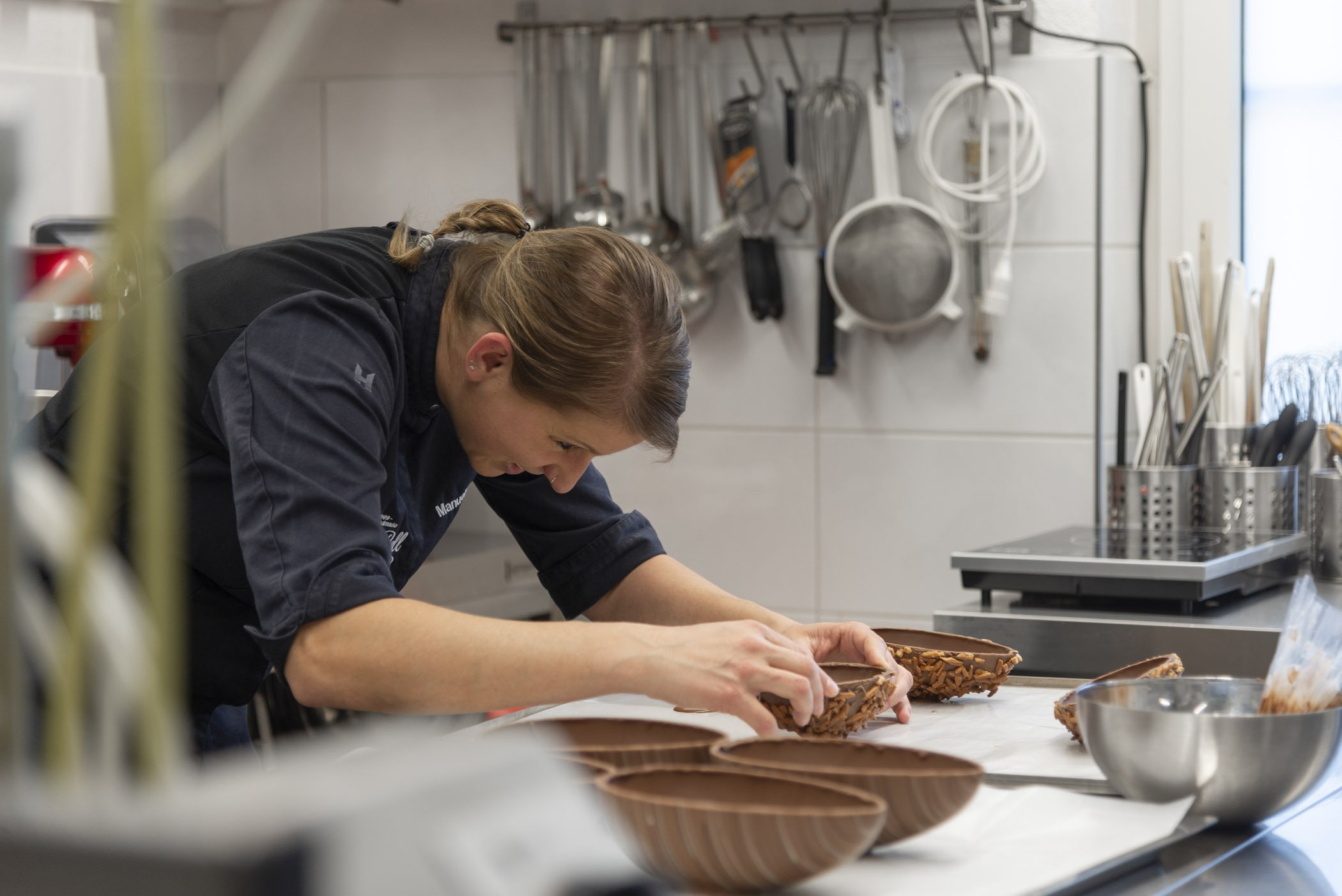 Konditorin formt Schokoladenformen in einer professionellen Küche.