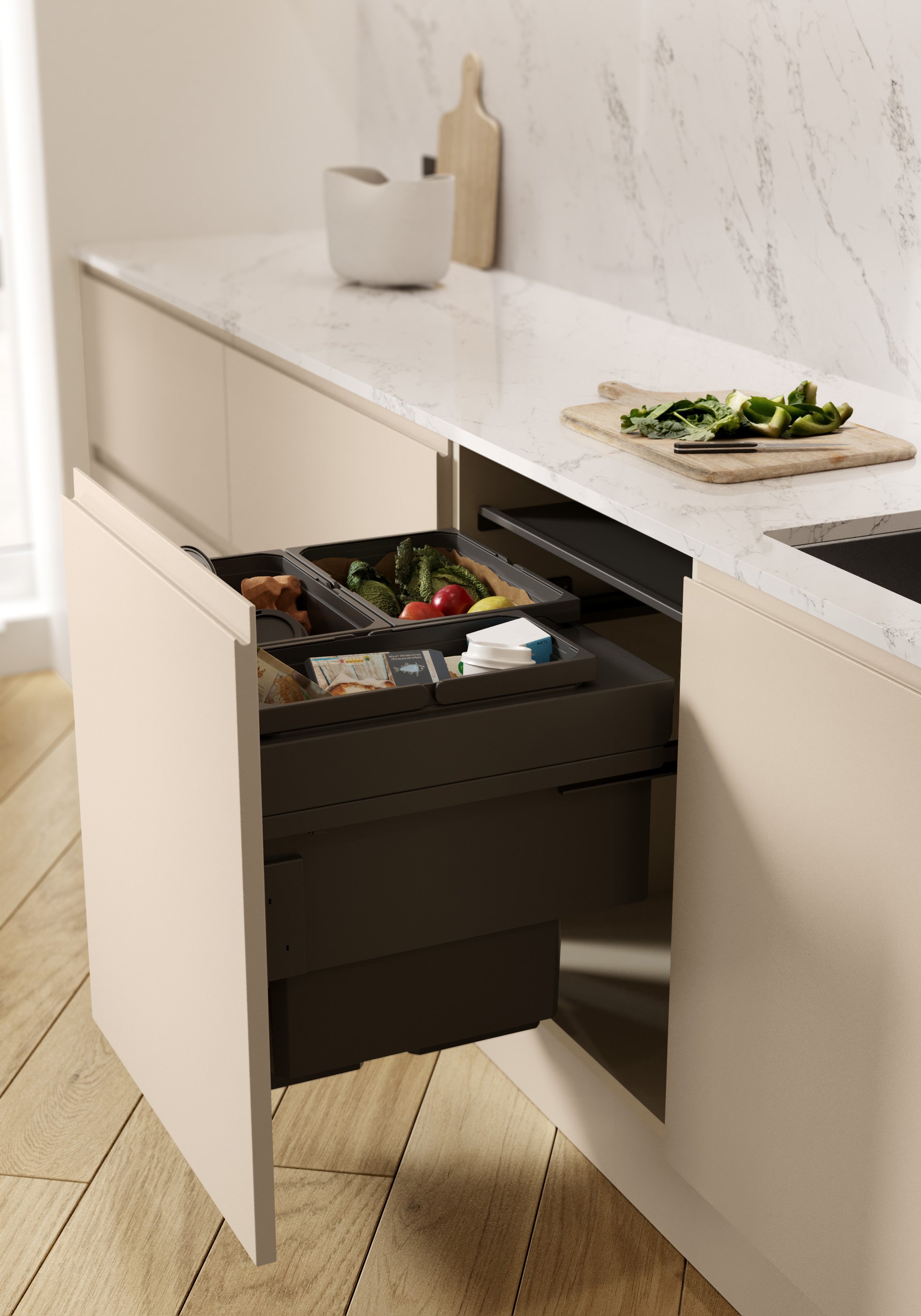 Modern kitchen with open drawer containing compartments for food waste and recyclables, marble countertop, cutting board with chopped vegetables, and decorative kitchen items.