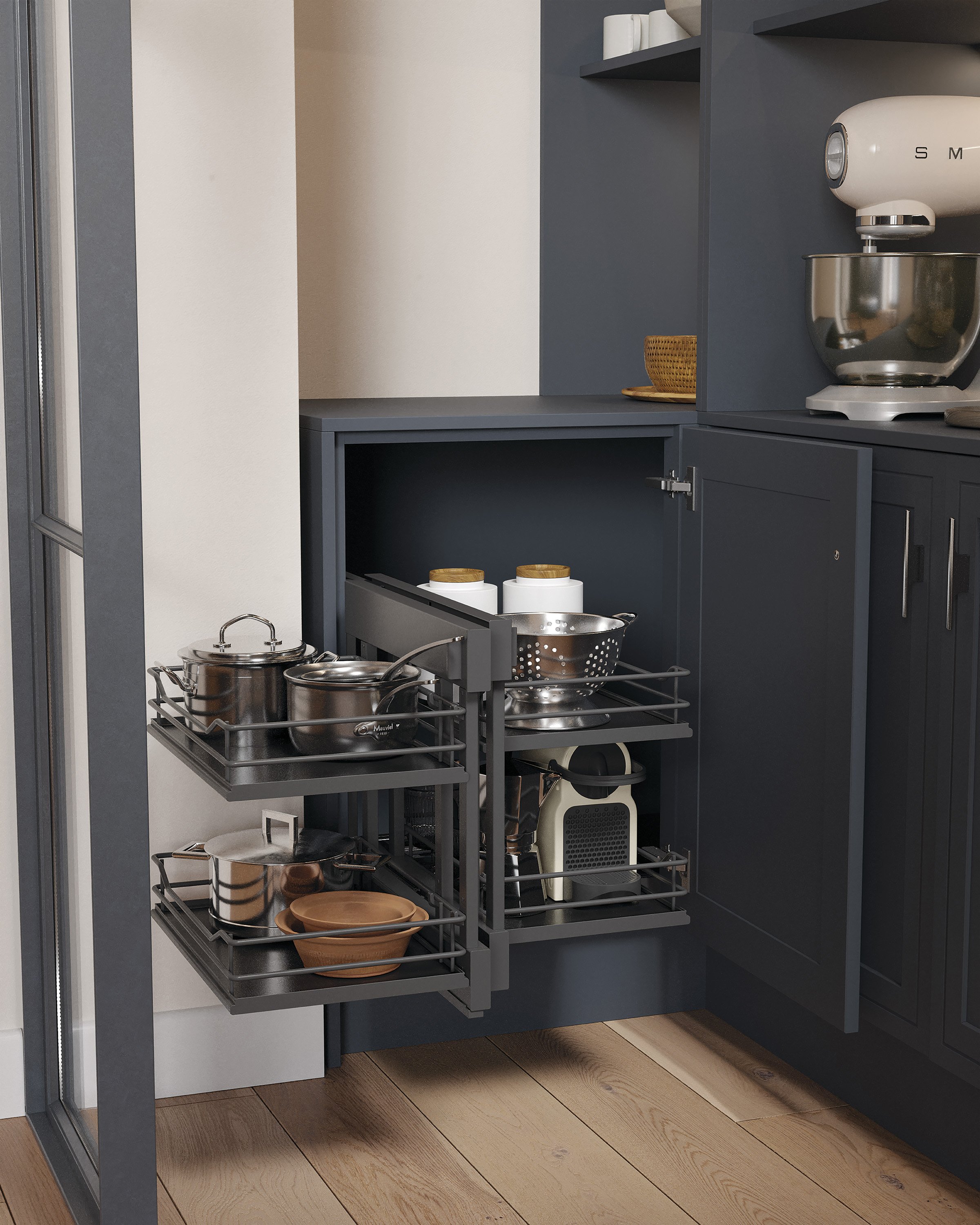 Kitchen cabinet with pull-out shelves containing cookware, pots, bowls, and a colander, next to a countertop with a stand mixer.