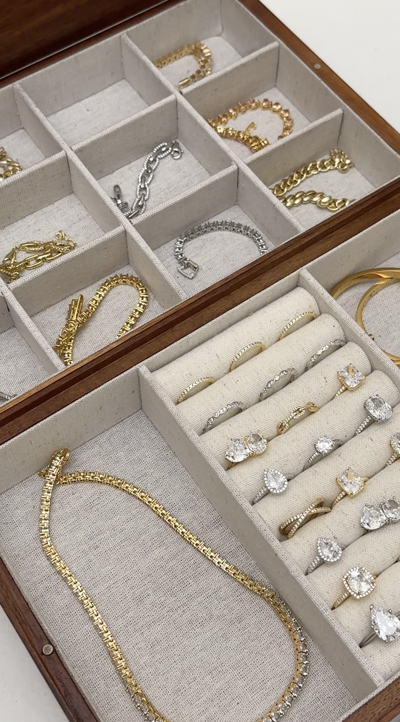 Jewelry box with multiple sections containing gold, silver, and diamond rings, bracelets, and necklaces.