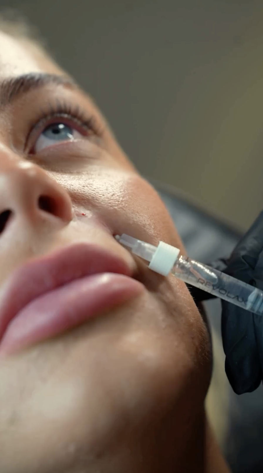 Close-up of a person receiving a nasal swab test with a swab in their nose and a healthcare worker wearing gloves.