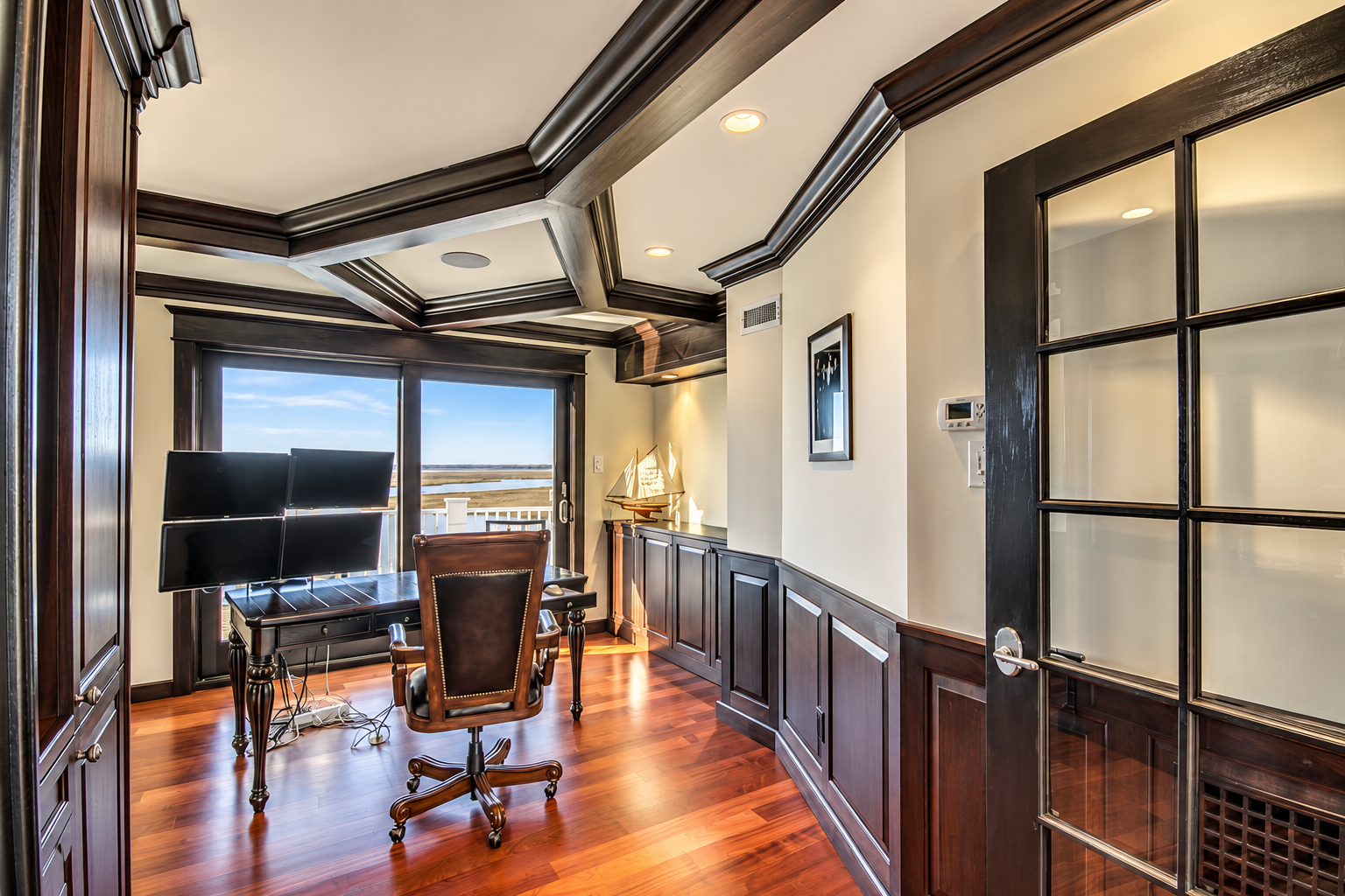 Home office with a coffered ceiling, dark custom millwork and water views in an Avalon, NJ custom home