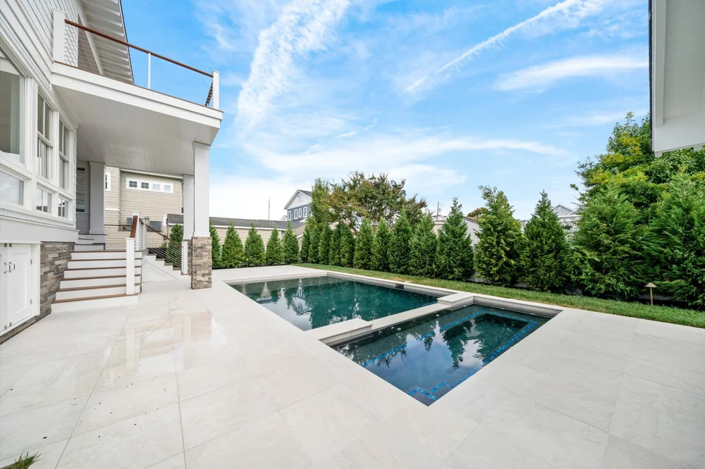 Built-in spa beside a gunite pool and a shingle-style home at the Jersey Shore