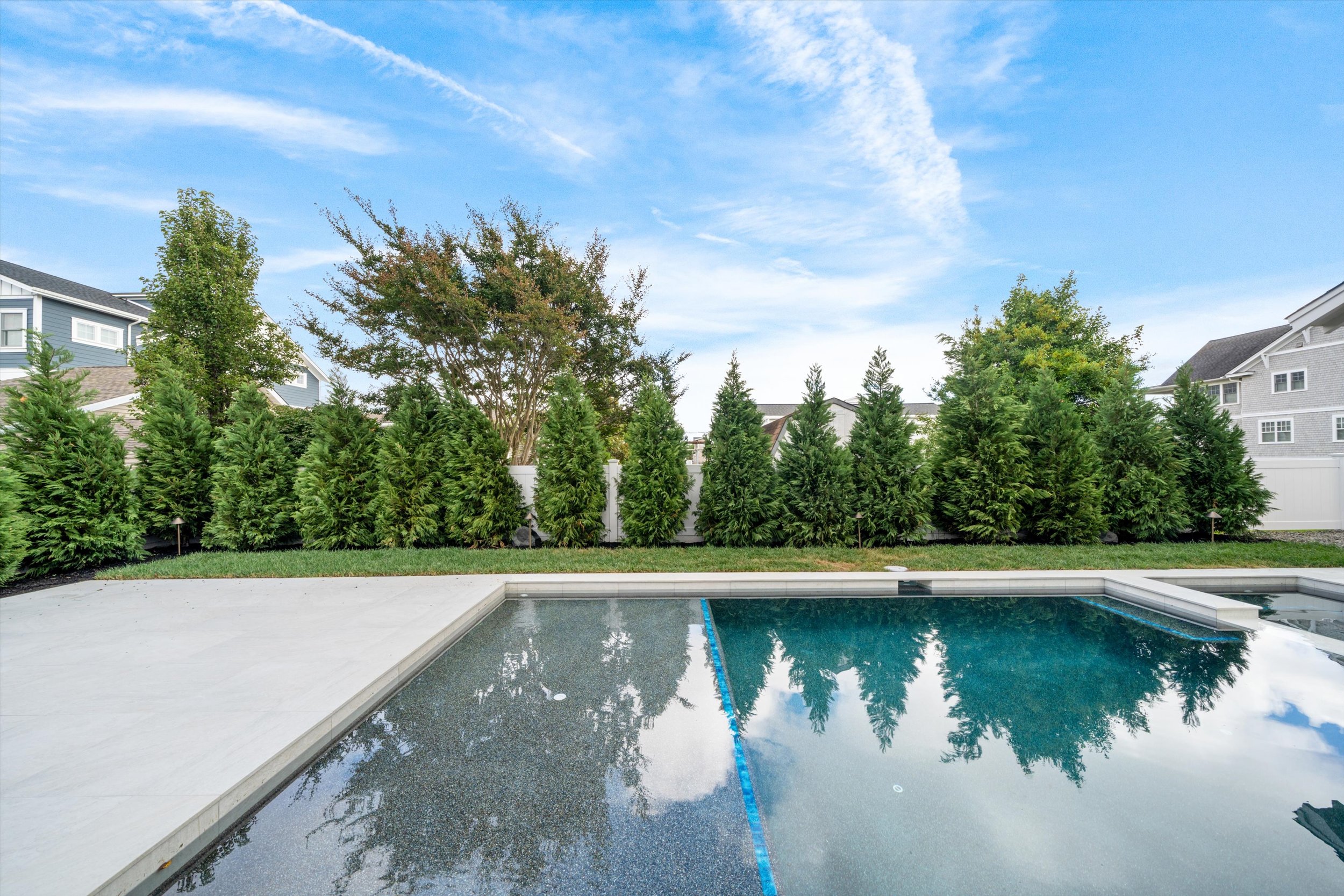 Pool and spa surrounded by porcelain pavers and evergreen privacy trees, 245 57th St, Avalon, NJ