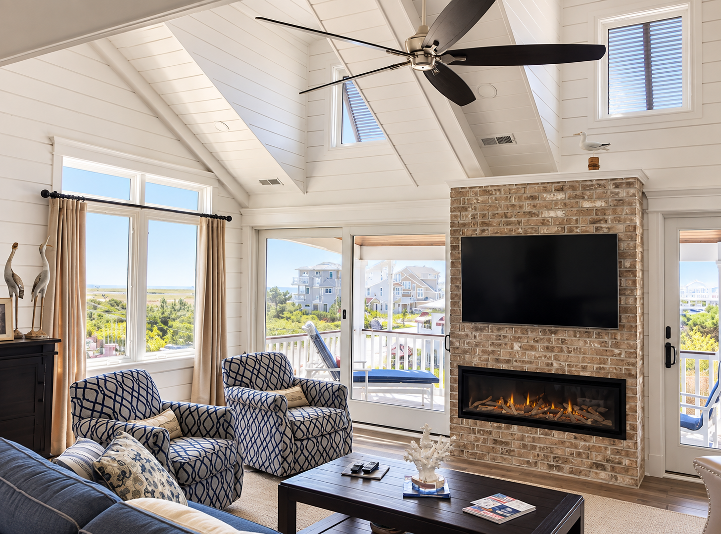 Vaulted living room with a brick fireplace wall and balcony doors in the renovated Sea Isle City duplex