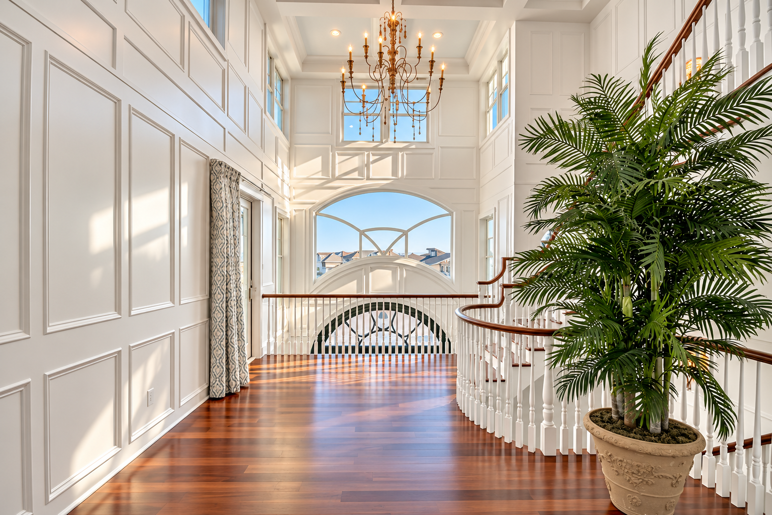 Two-story foyer with floor-to-ceiling millwork, a chandelier and a curved staircase in an Avalon, NJ custom home
