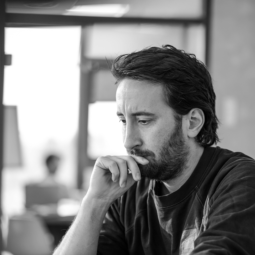 Schwarzweißfoto eines Mannes in nachdenklicher Pose in einem modernen Büro.