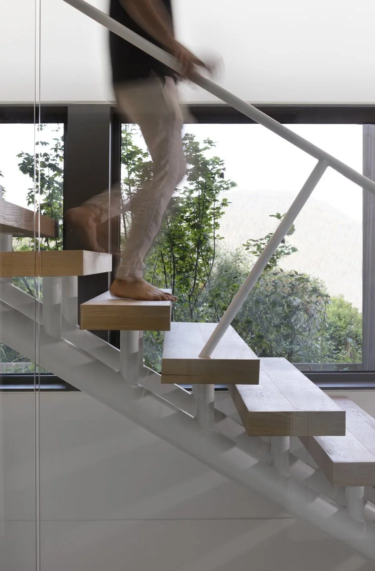 Open timber stair treads beside full-height glazing at Deep Cove.