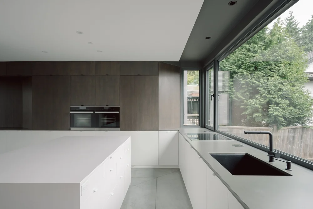 Gladstone kitchen with a white island, dark cabinetry and a long window overlooking greenery.
