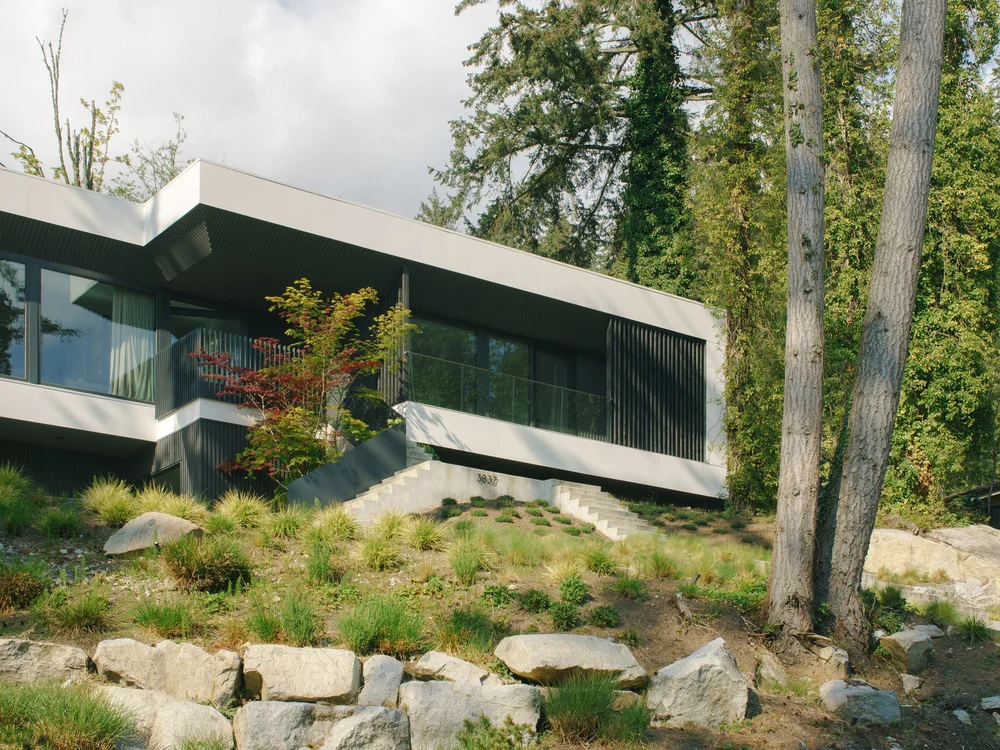 Bayridge house with angular rooflines and broad windows above a planted rock garden.