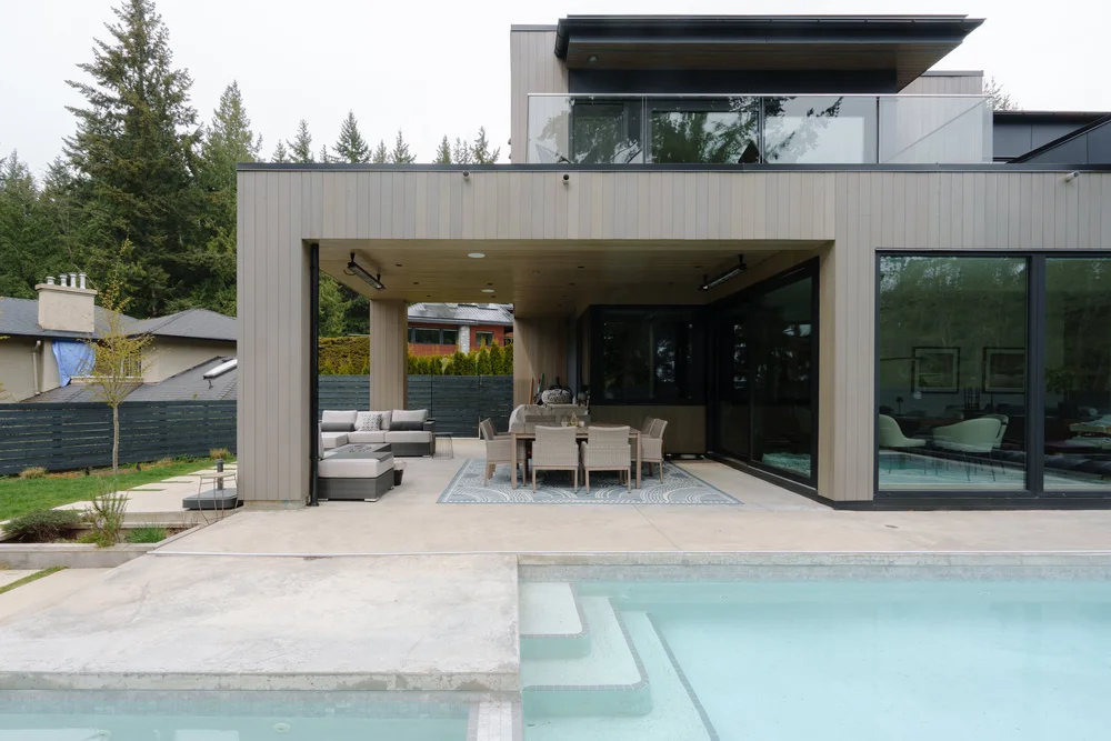 Woodgreen’s covered outdoor dining terrace beside a pool, with a balcony above.