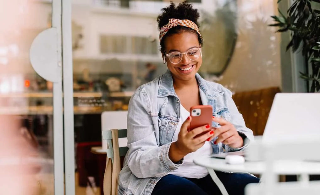 A VA in a modern café workspace with laptop, glasses, and denim jacket
