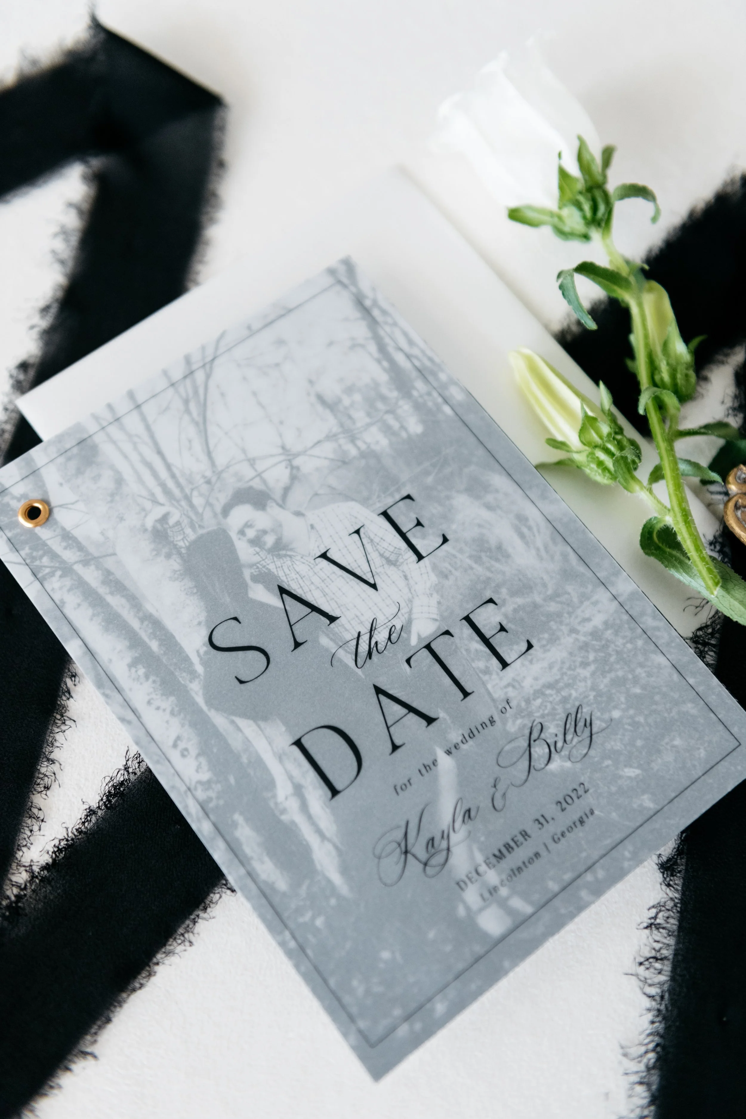 Wedding save-the-date card on fabric with a white rose and black ribbon. New York, New York