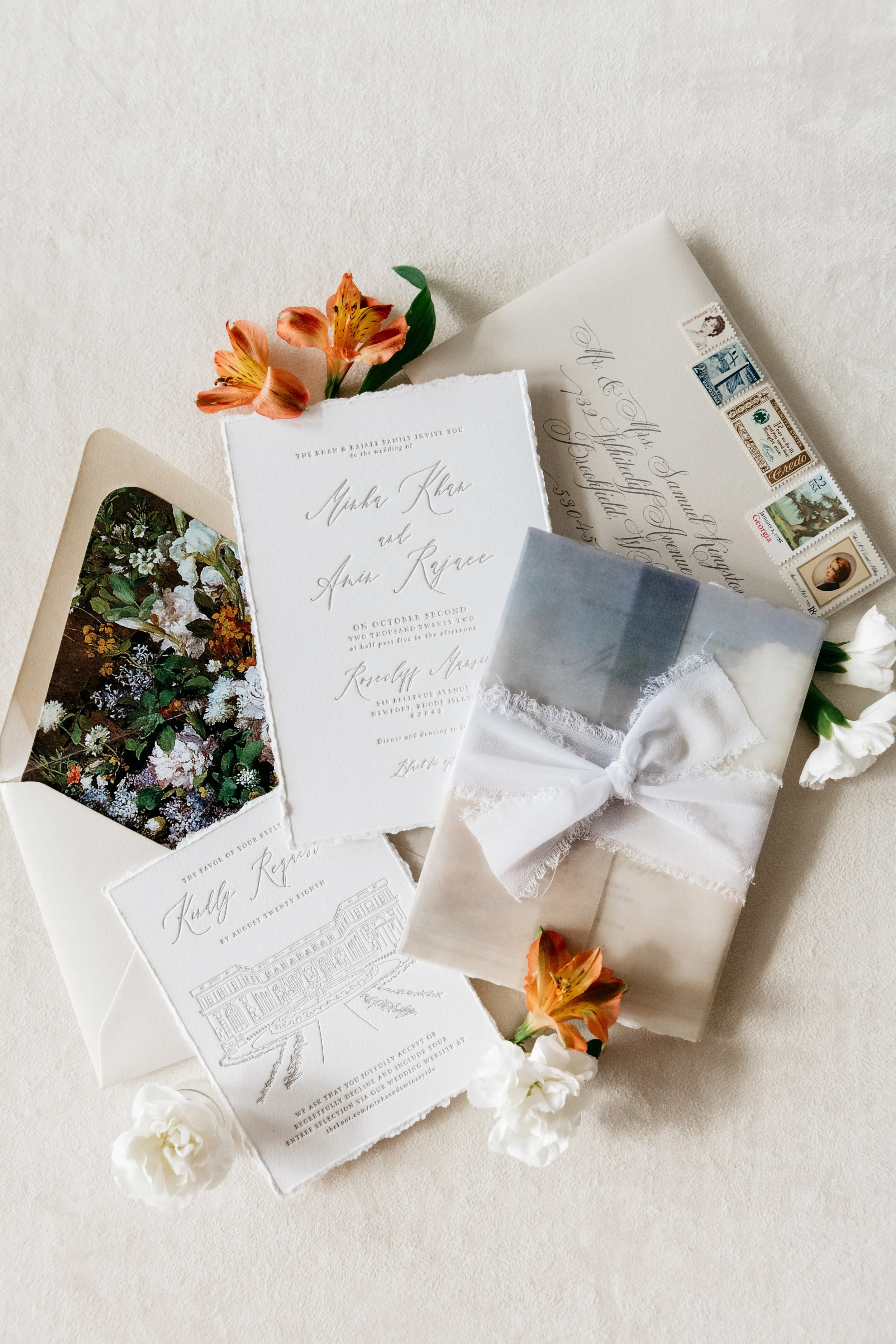 Elegant wedding invitations with calligraphy, floral accents, and envelopes on a textured surface. Newport, Rhode Island