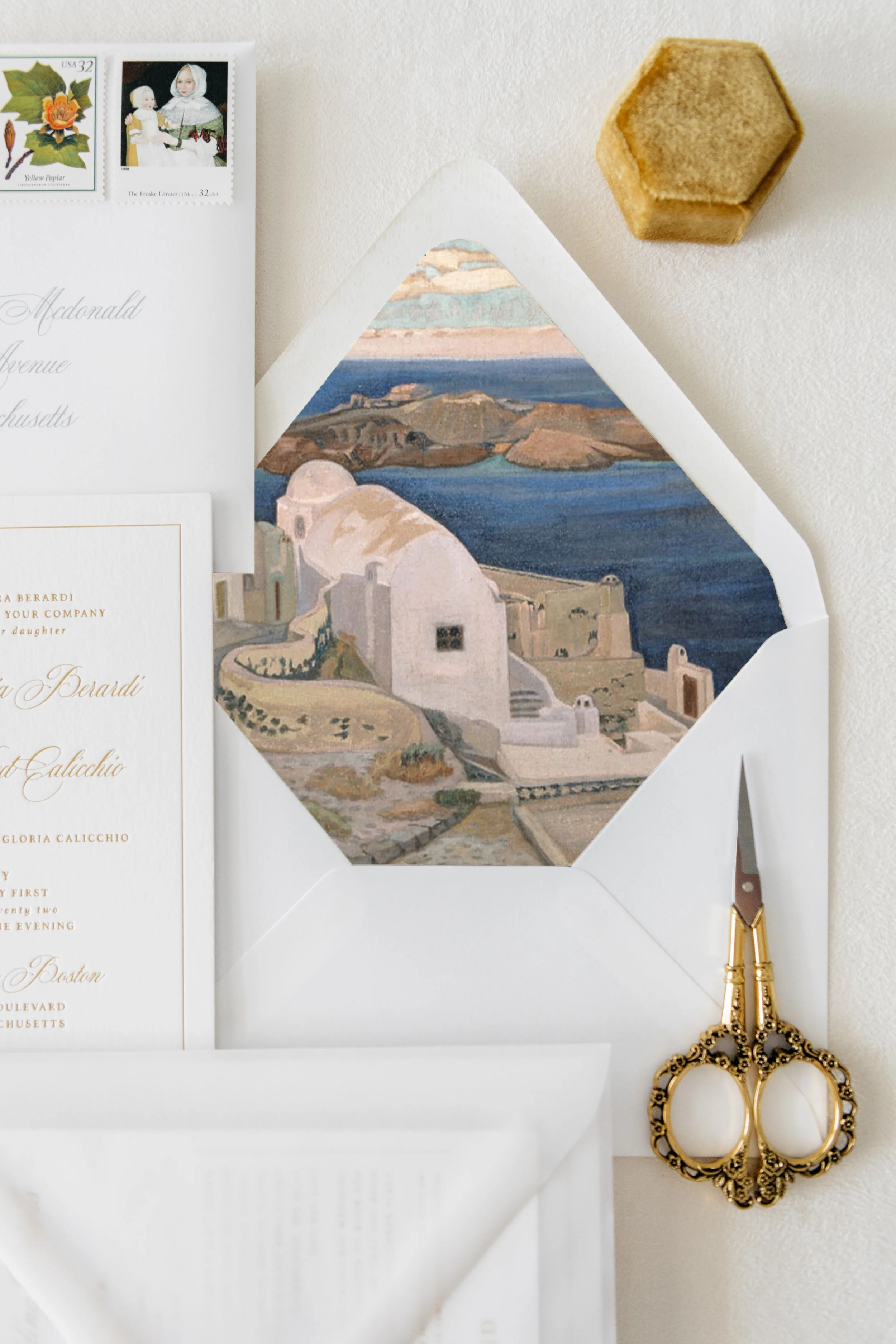 Vintage wedding invitation suite with envelope, decorative scissors, and stamps, featuring a scenic illustration of Santorini, Greece. Greek destination wedding