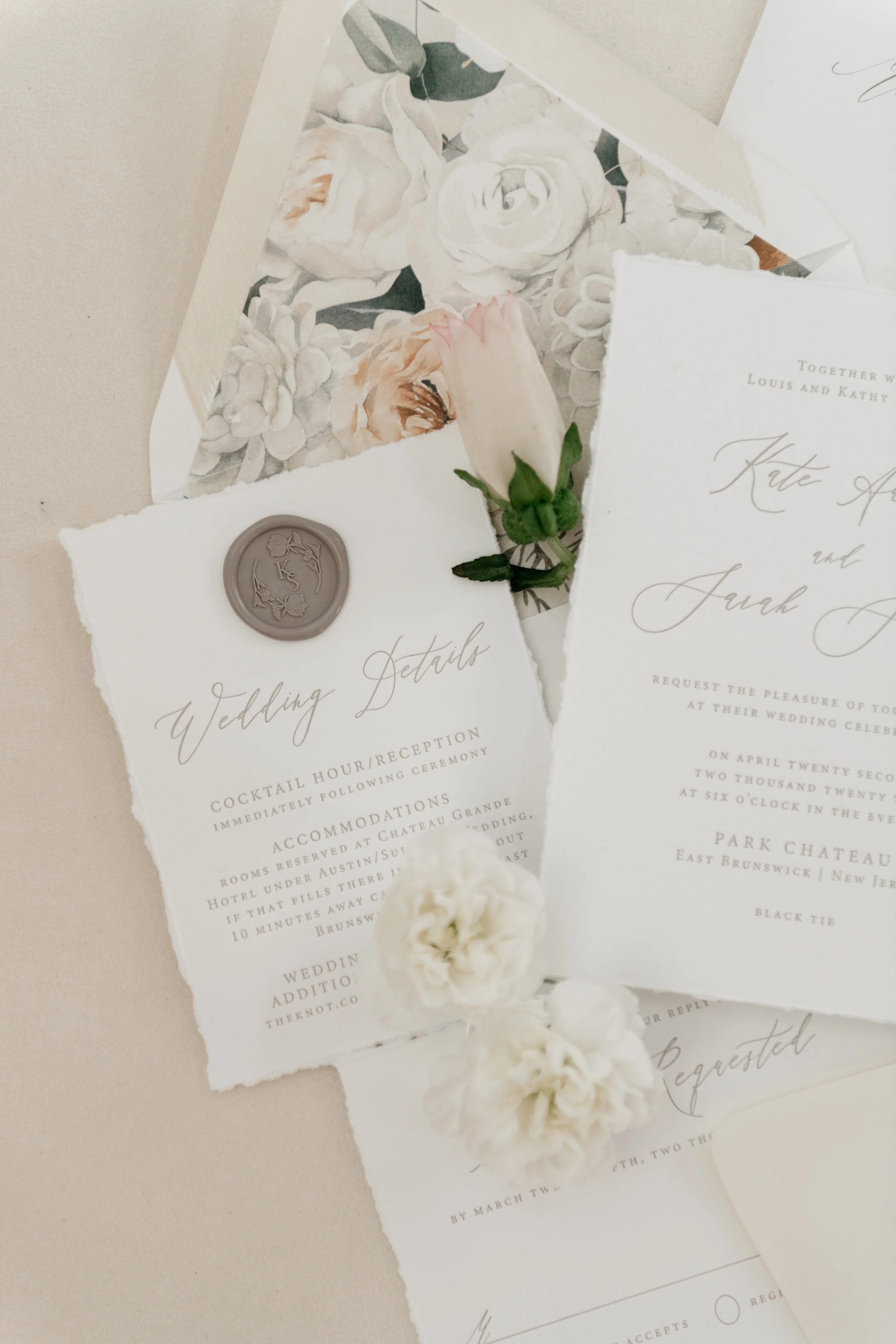 Flat lay of elegant wedding stationery with floral designs, wax seal, white flowers, and delicate script text. New Brunswick, New Jersey