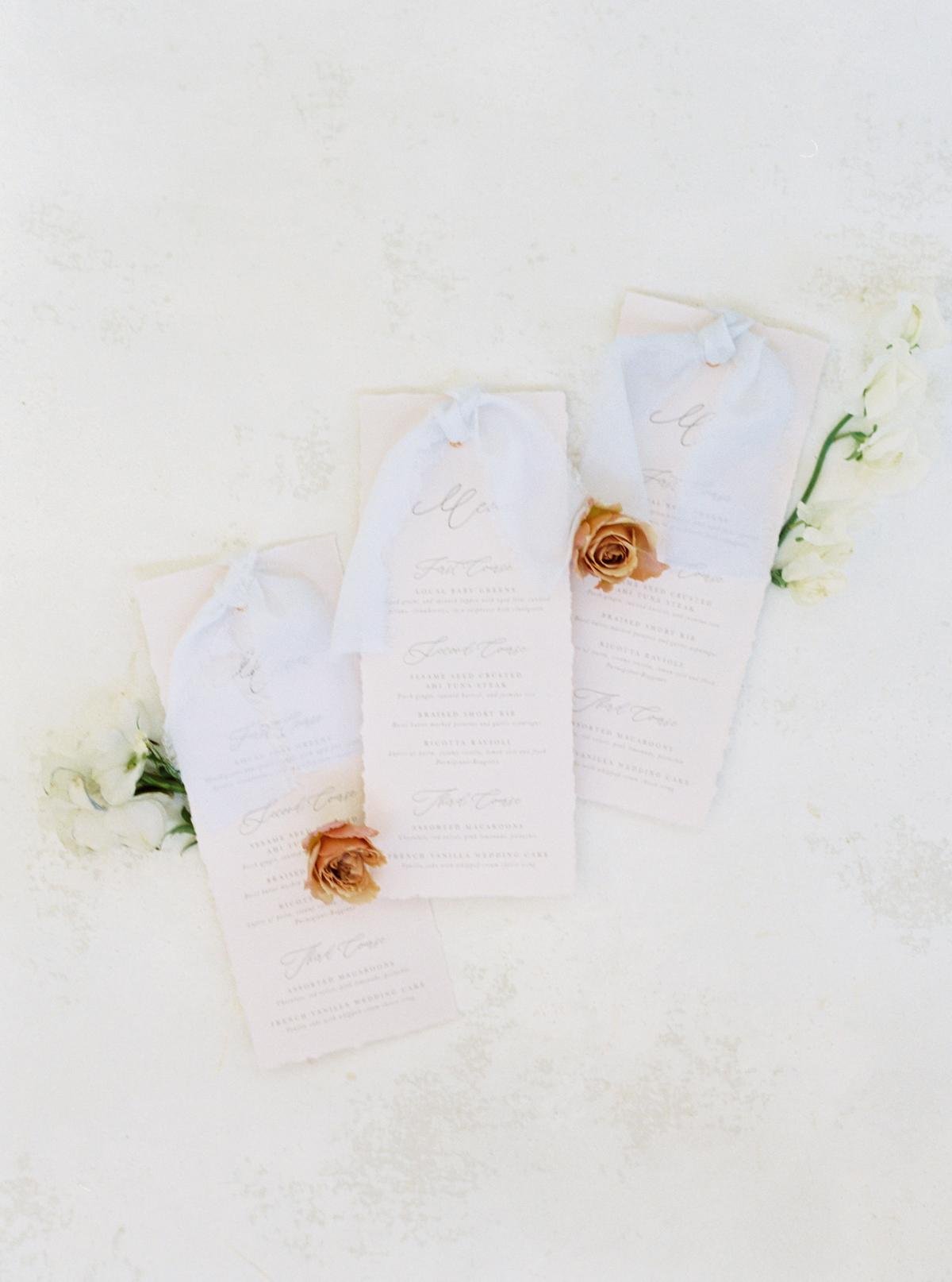 Elegant wedding menus with soft fabric accents and decorative flowers on a textured background. Scottsdale, Arizona 