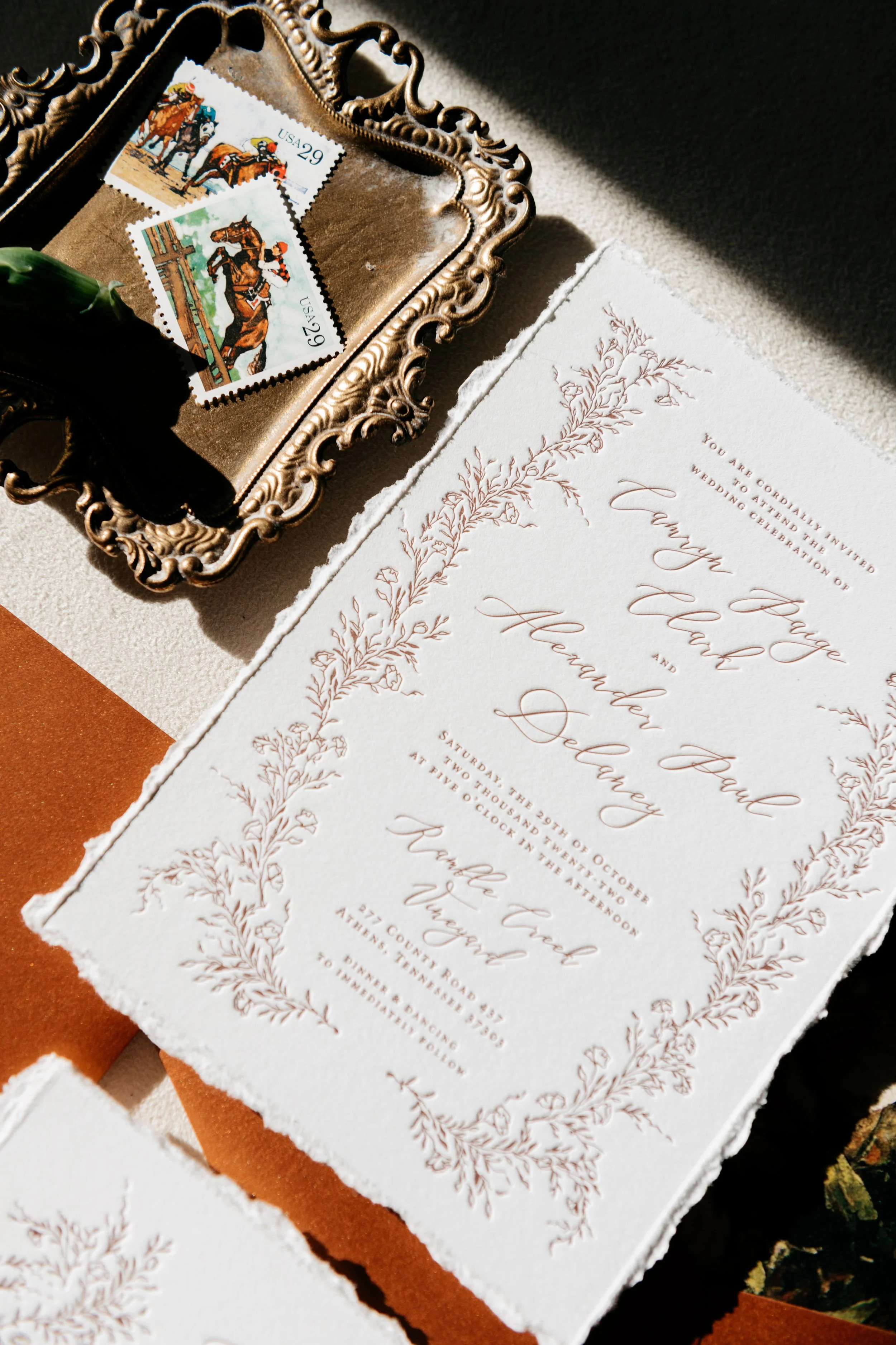 Wedding invitation with botanical border, vintage stamps featuring horses on an ornate tray.