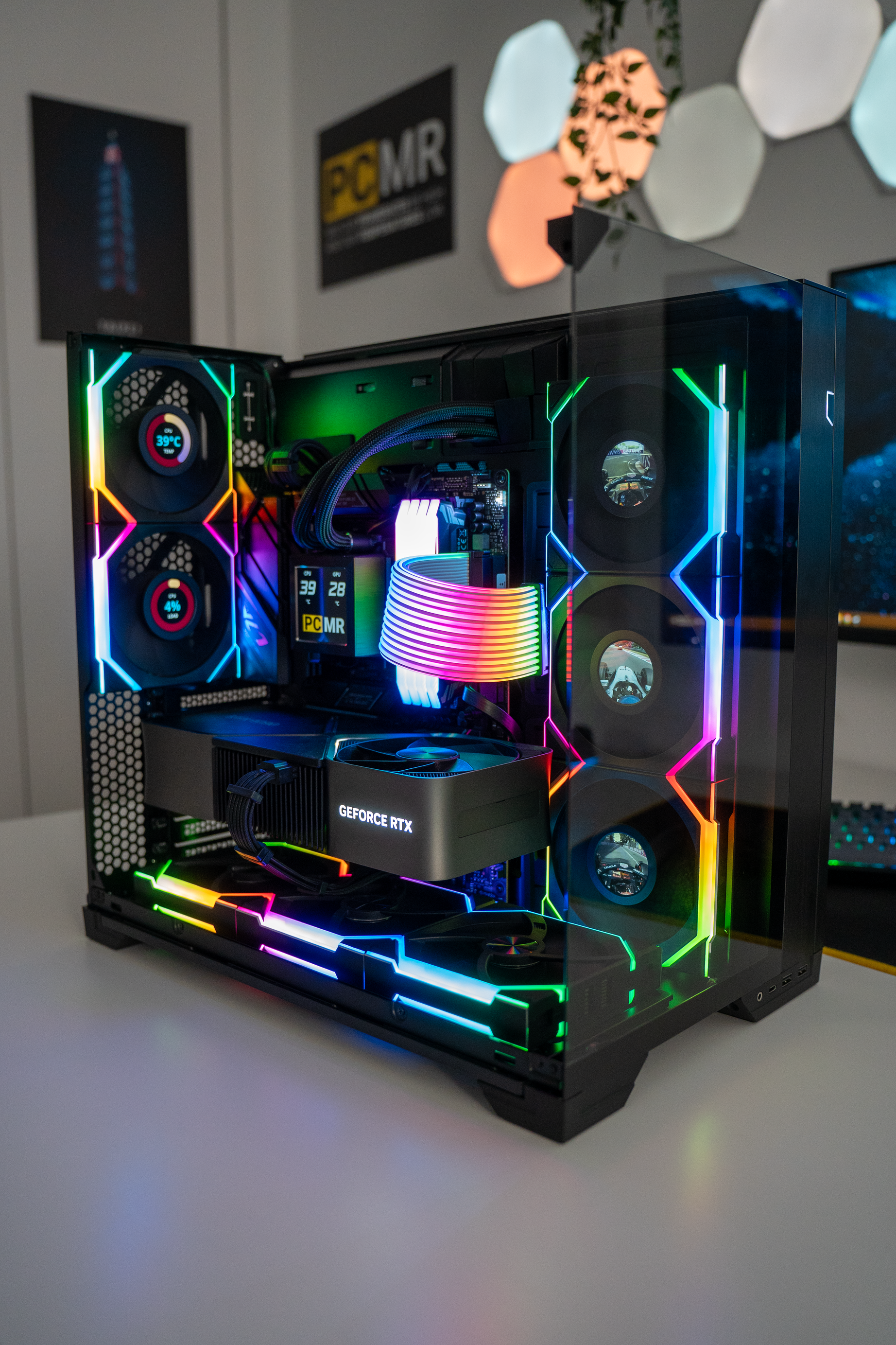 A custom gaming computer with RGB lighting, featuring a graphics card labeled GeForce RTX, inside a glass case with multiple fans and a rainbow-colored cable.