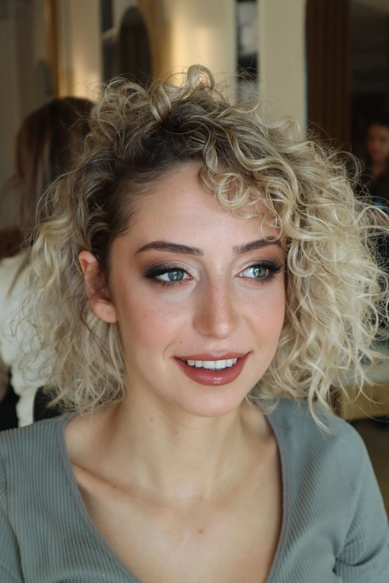 Mulher jovem com cabelo loiro encaracolado e maquilhagem deslumbrante.