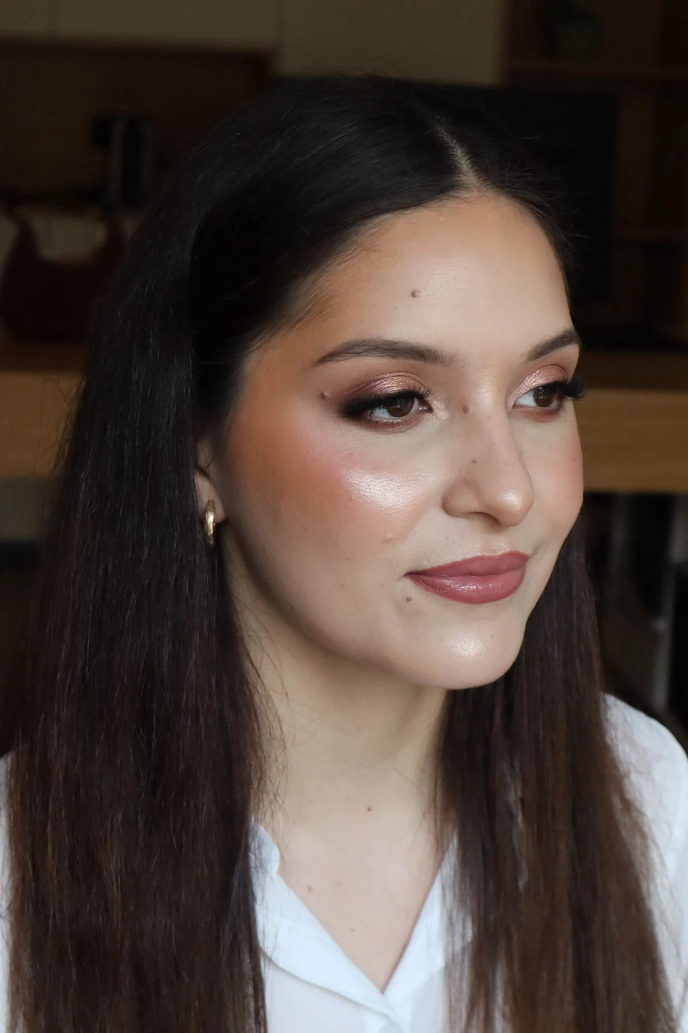 Mulher com maquiagem suave e cabelo longo, usando blusa branca.