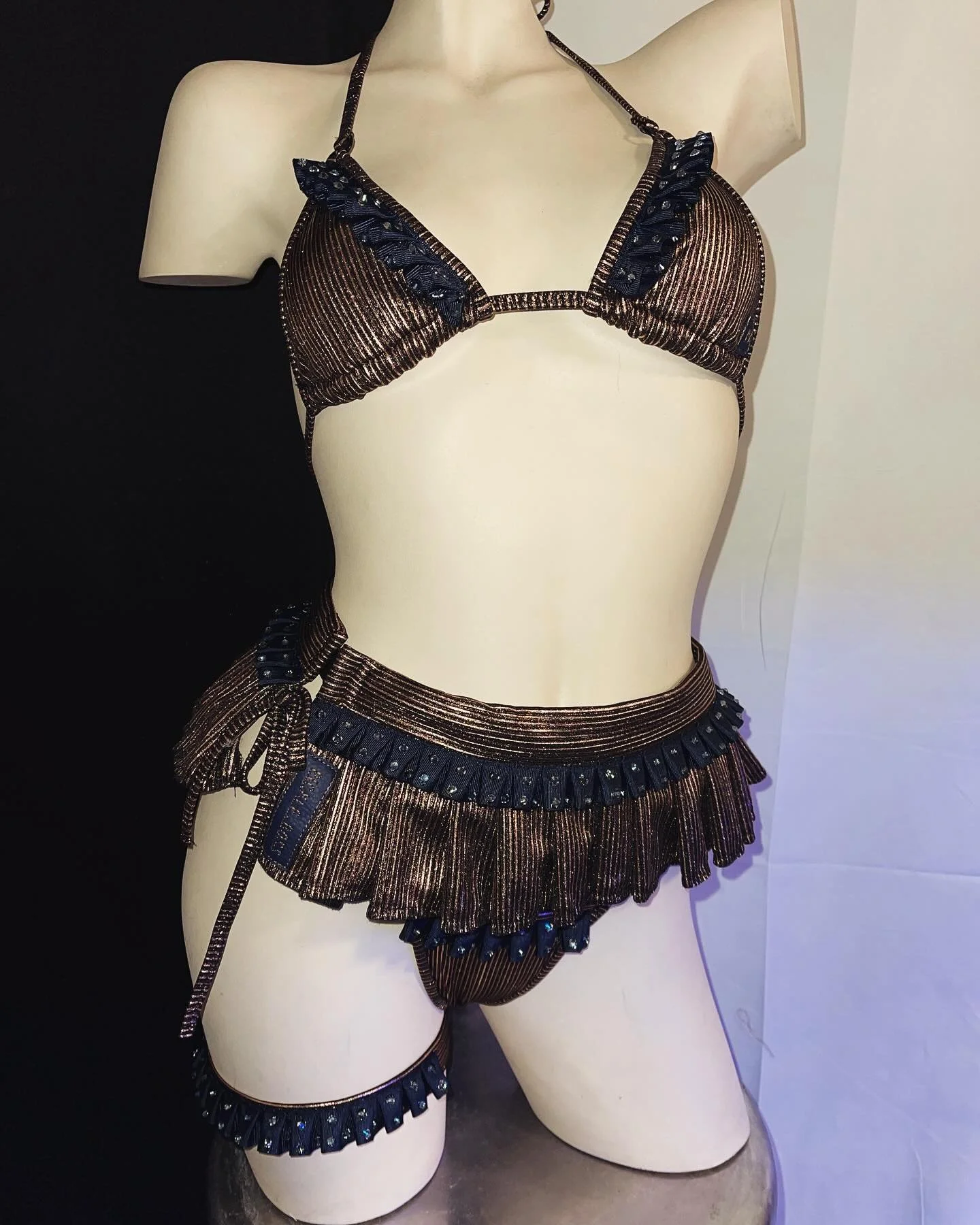 Mannequin wearing a bronze and black frilled bikini with skirt accents.