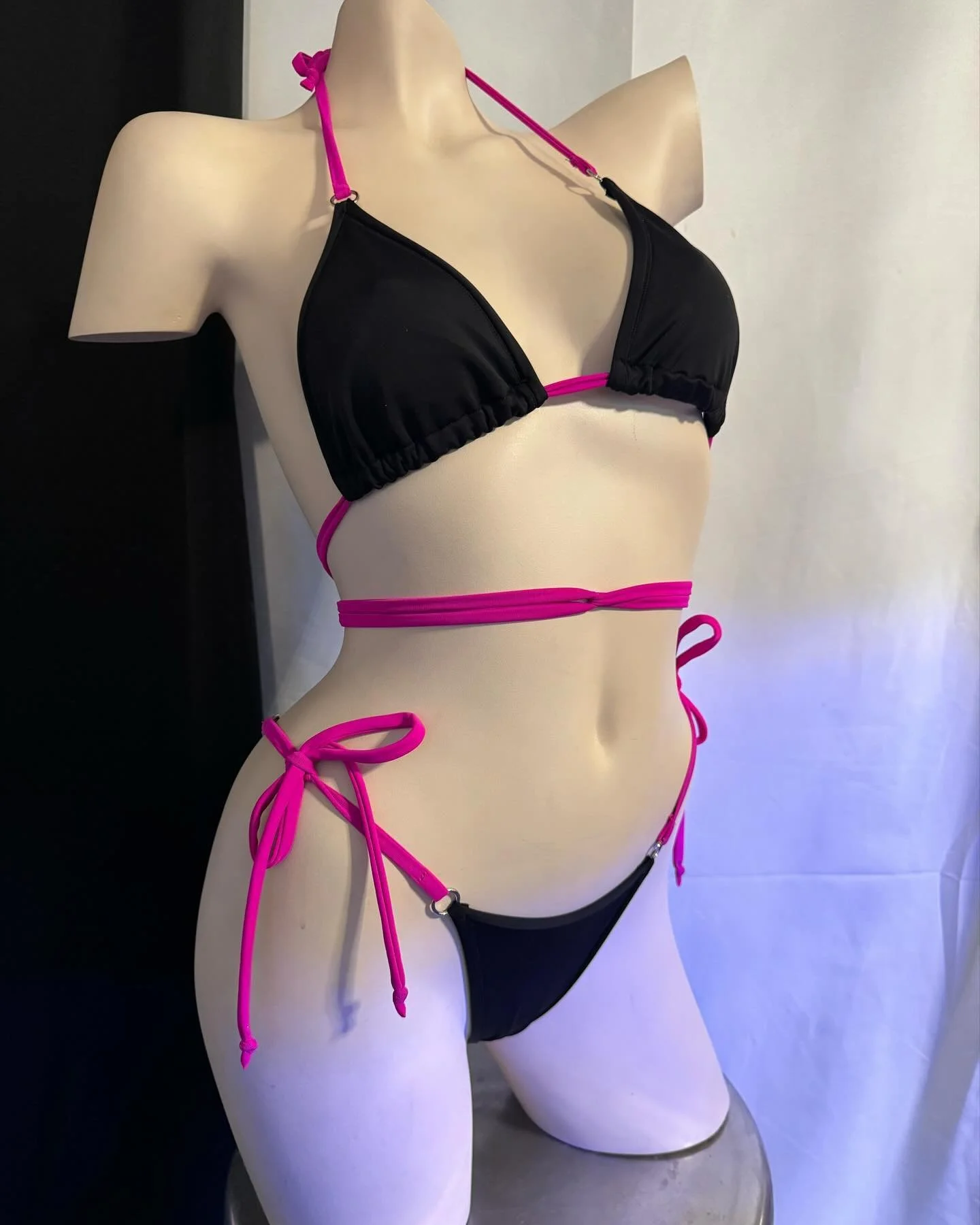 Mannequin wearing a black bikini with pink straps against a white background.