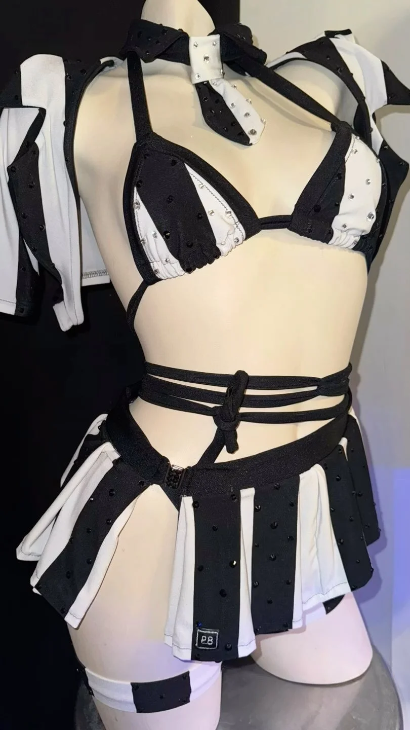 Black and white studded bikini outfit on a mannequin, featuring a tie and skirt with straps.